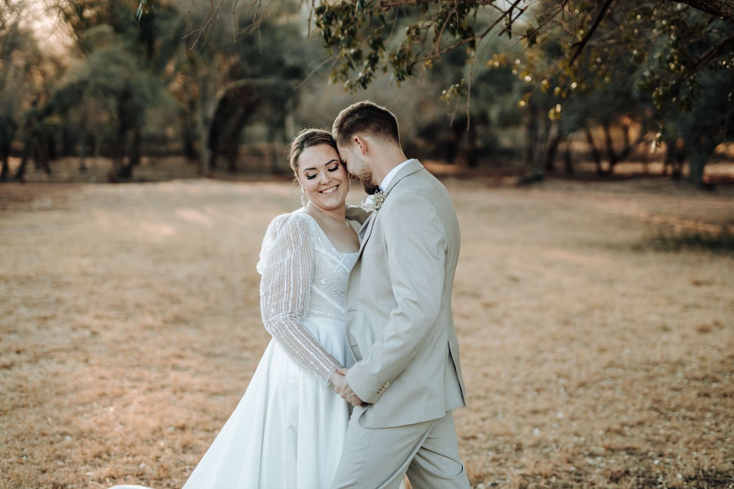 Tender embrace between newlyweds in a dreamy autumn forest setting.
