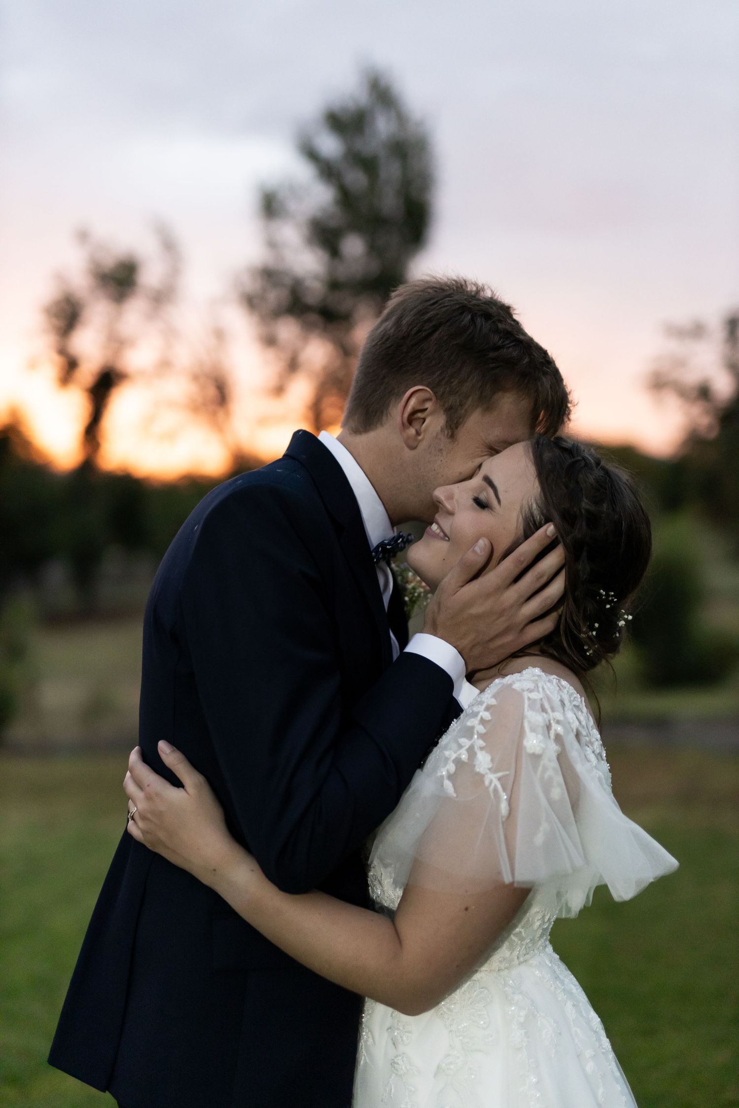 Romantic sunset wedding portrait showing tender moment between bride and groom.
