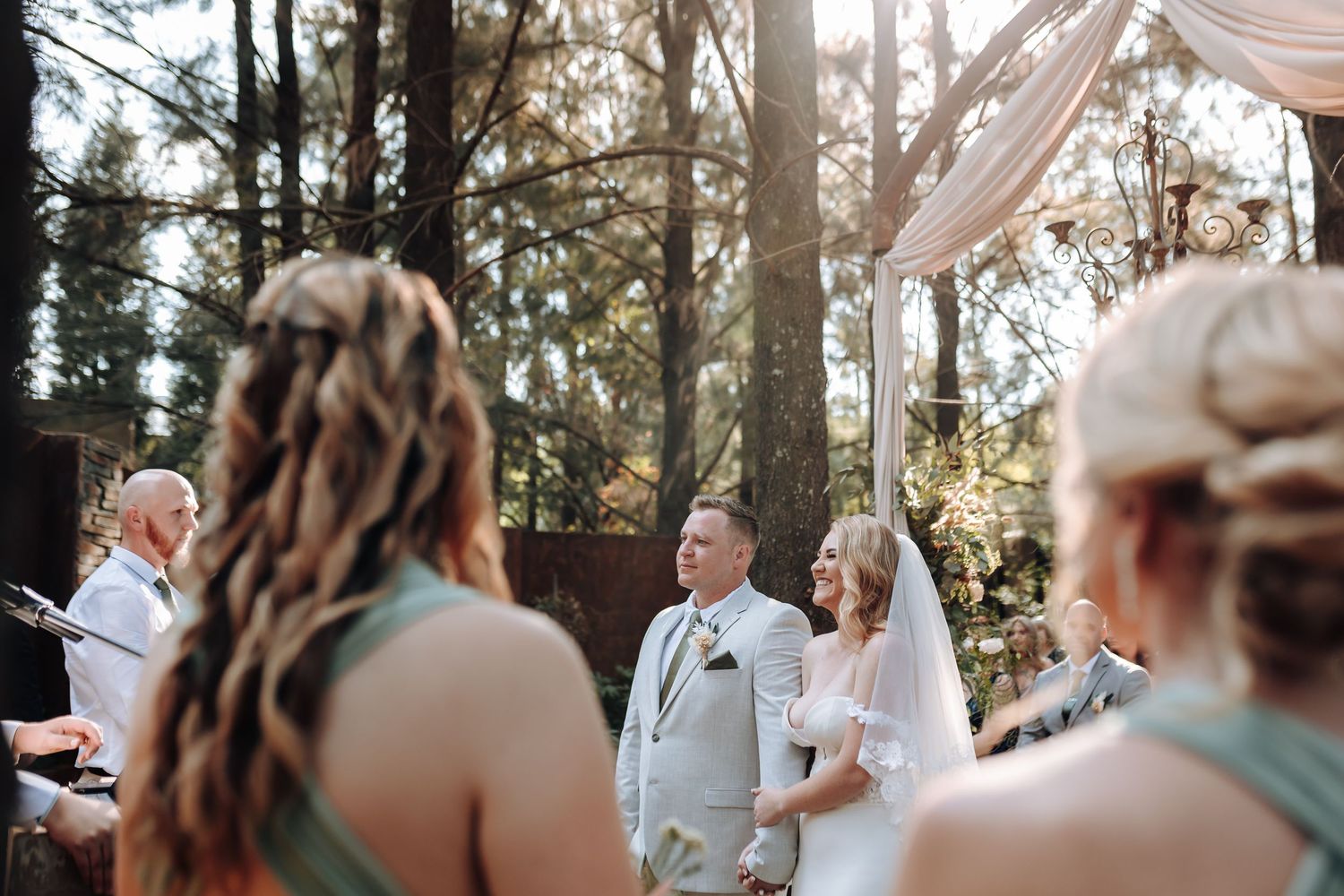 Beautiful woodland wedding ceremony with sunlight filtering through pine trees.