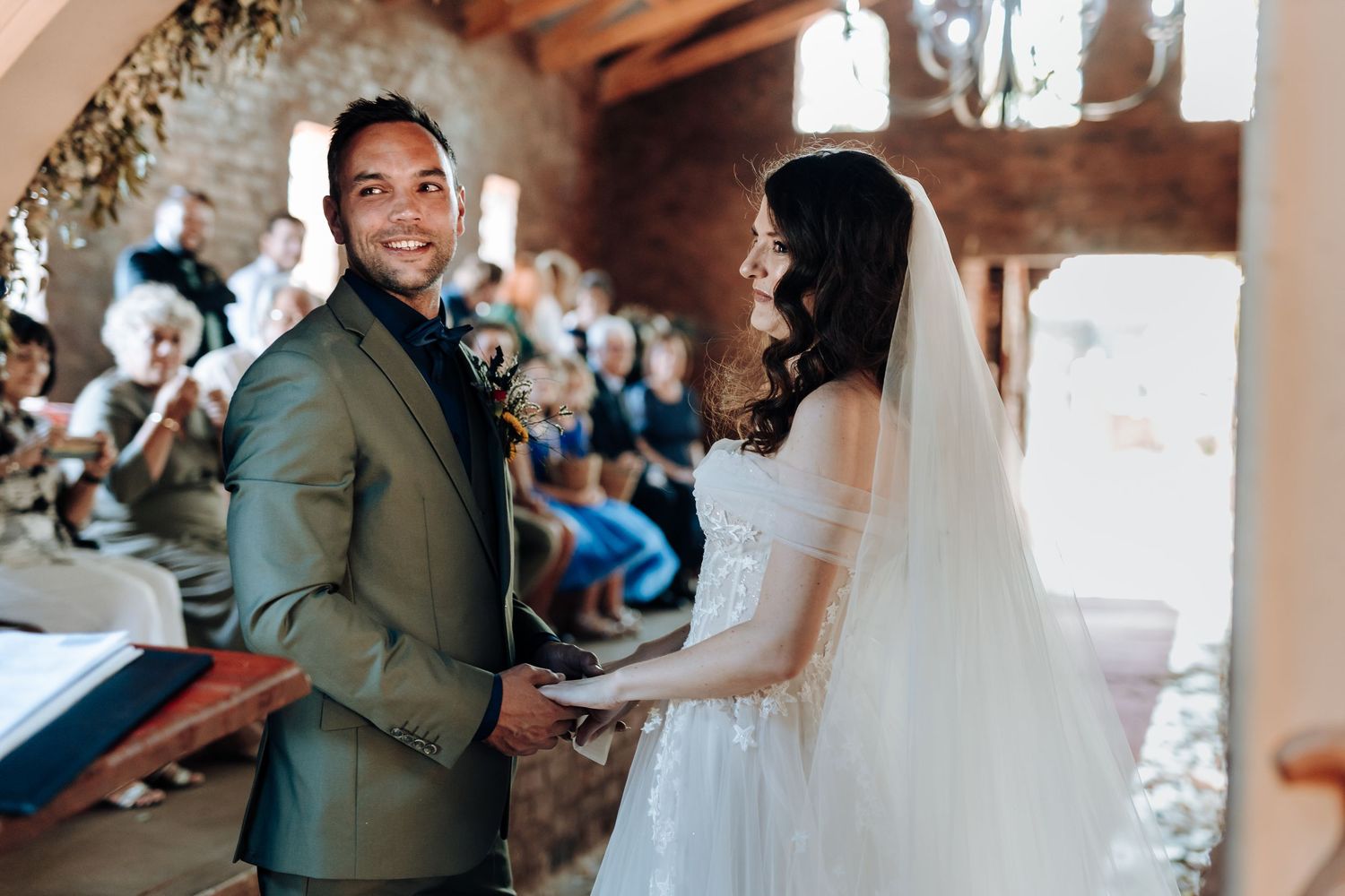 Bride and groom exchange joyful glances during their wedding ceremony under an archway.