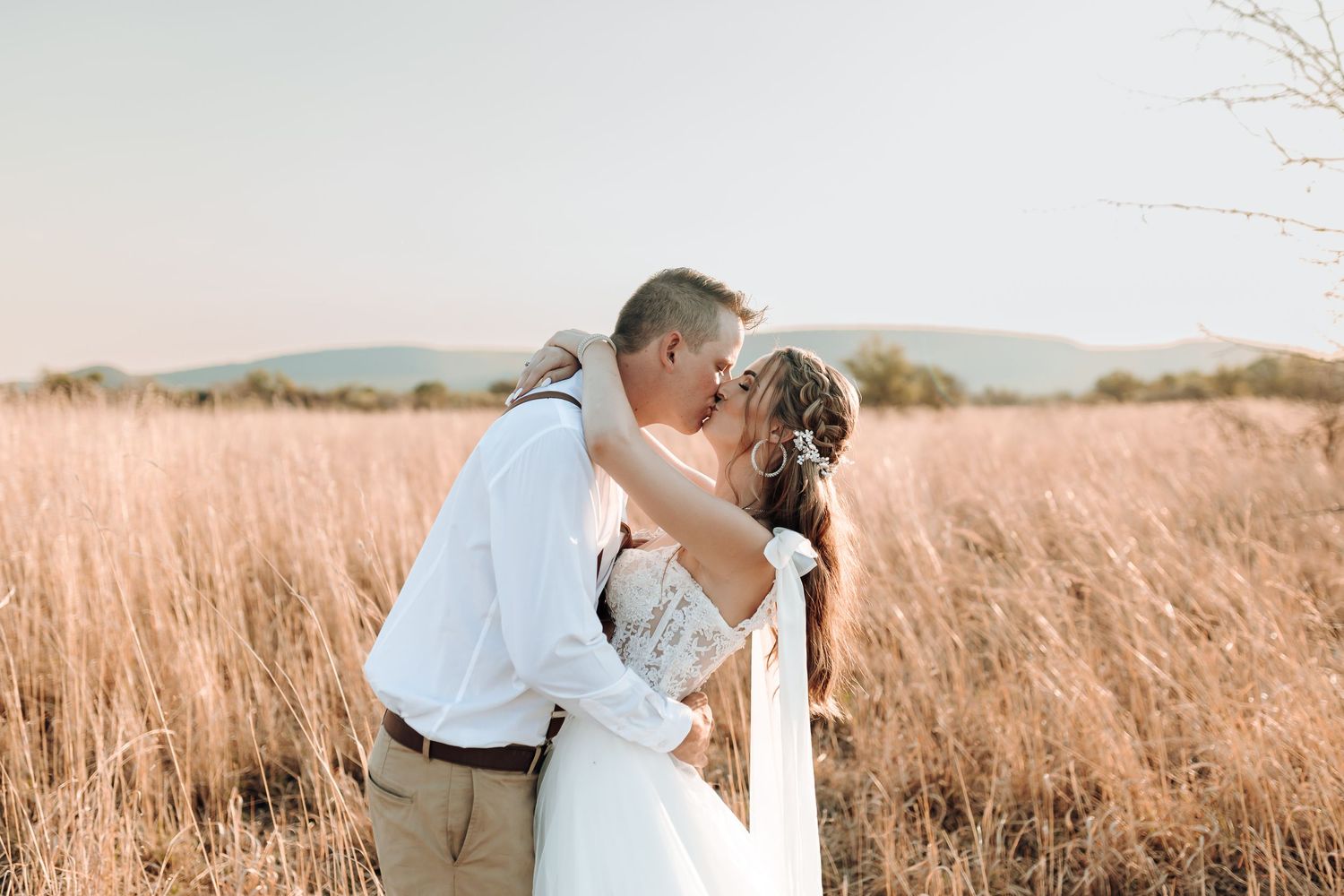 Romantic sunset wedding portrait in field with warm golden tones.