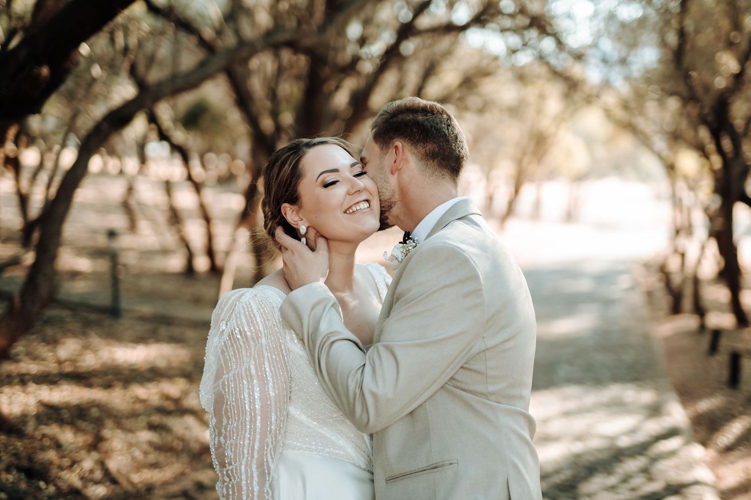 Intimate moment between newlyweds in sunlit forest setting.