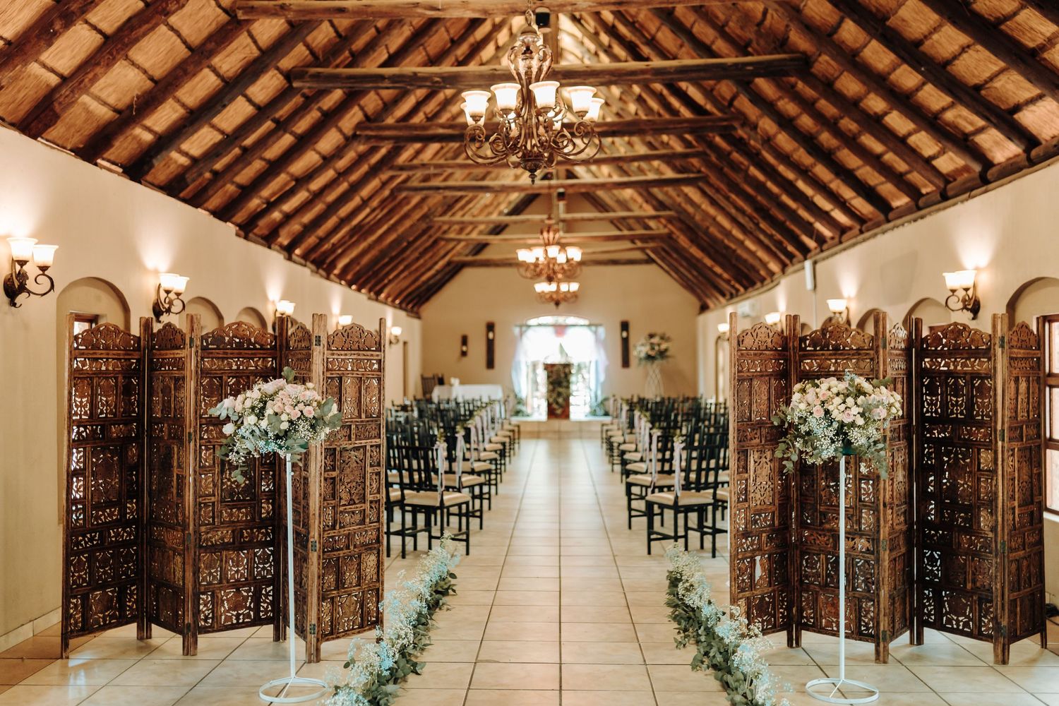 Elegant wedding ceremony venue with wooden dividers and floral aisle decorations.