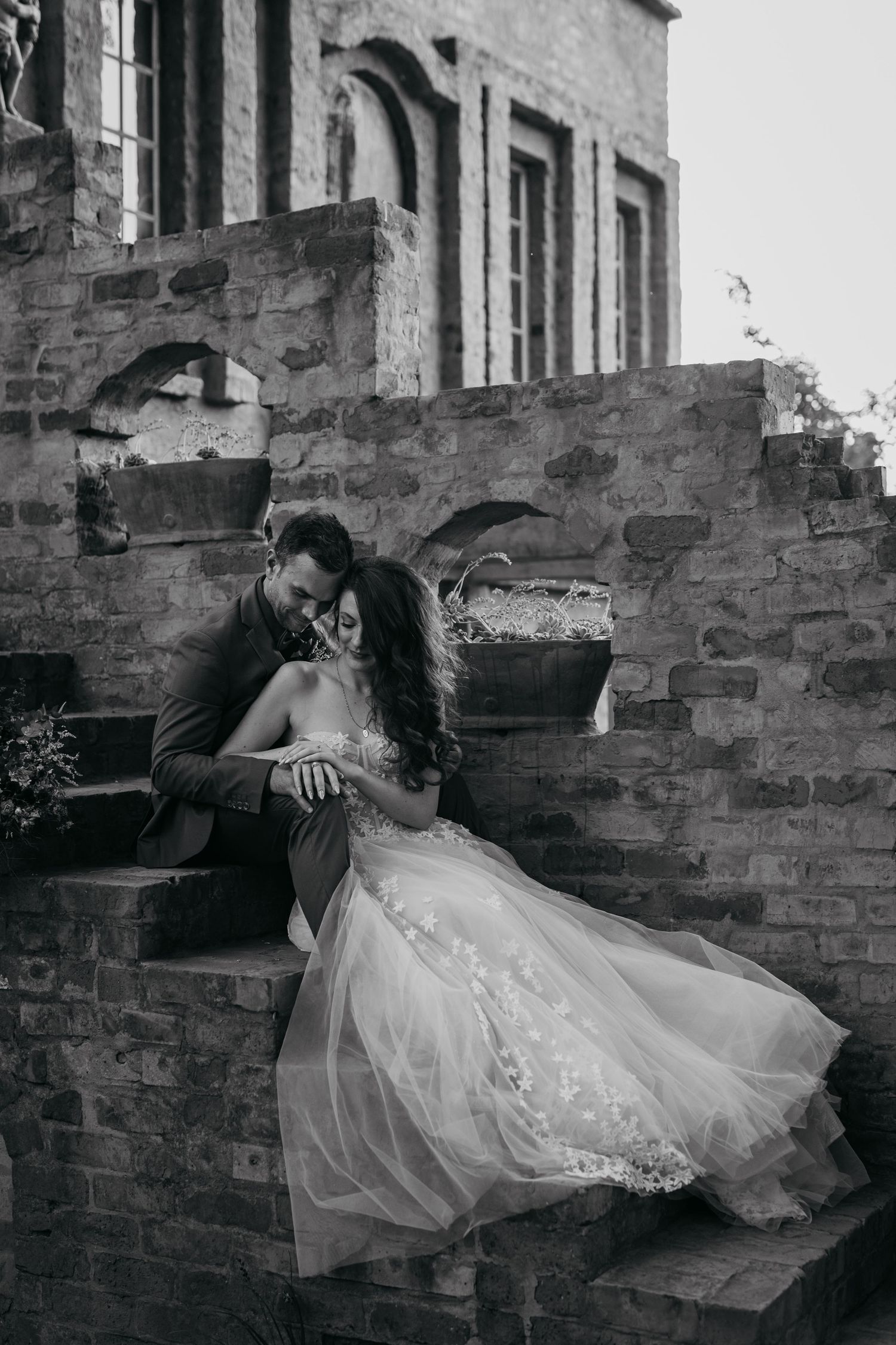 Black and white wedding portrait showcasing an intimate moment on stone steps.