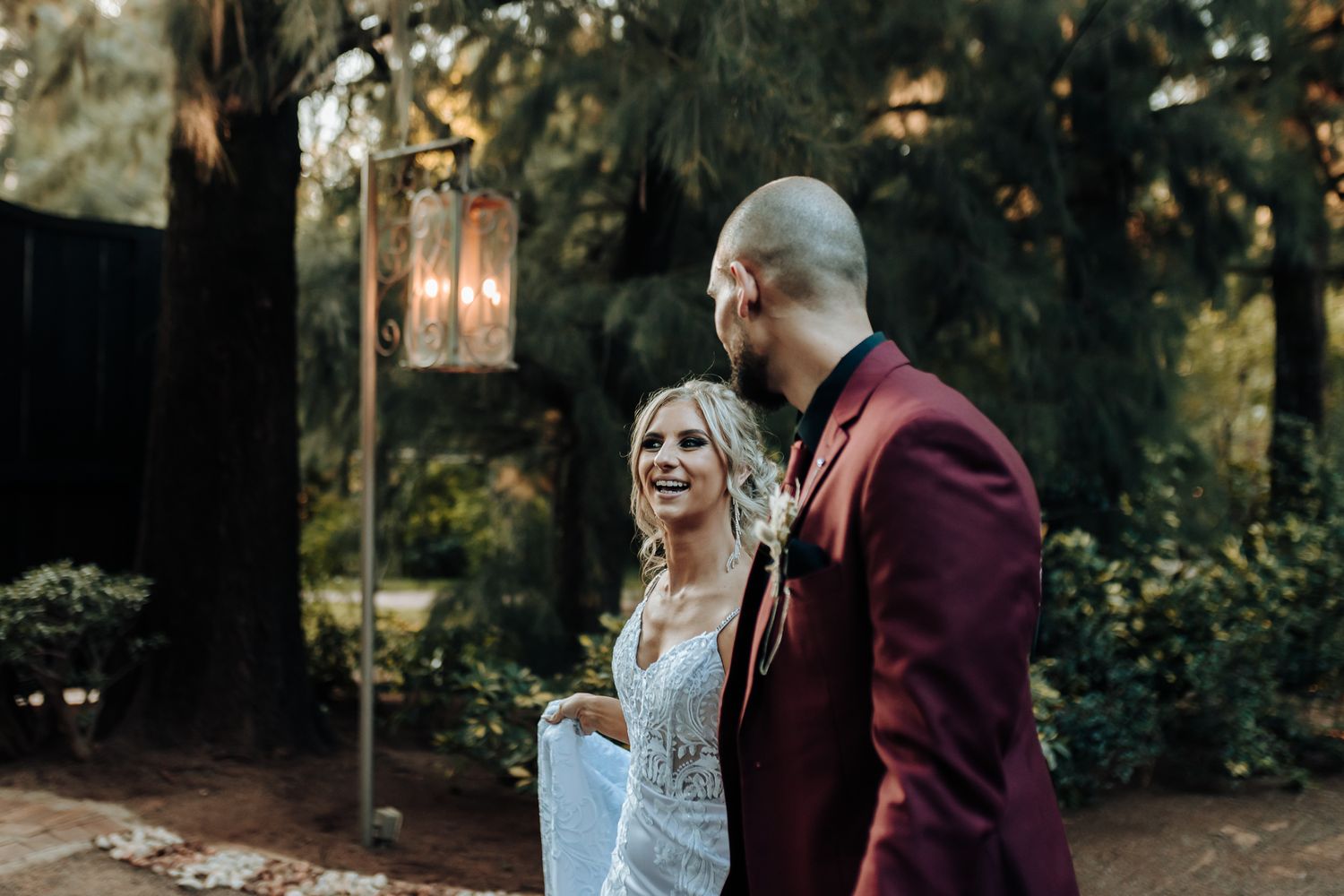 Evening wedding portrait with vintage lantern lighting in a garden setting.
