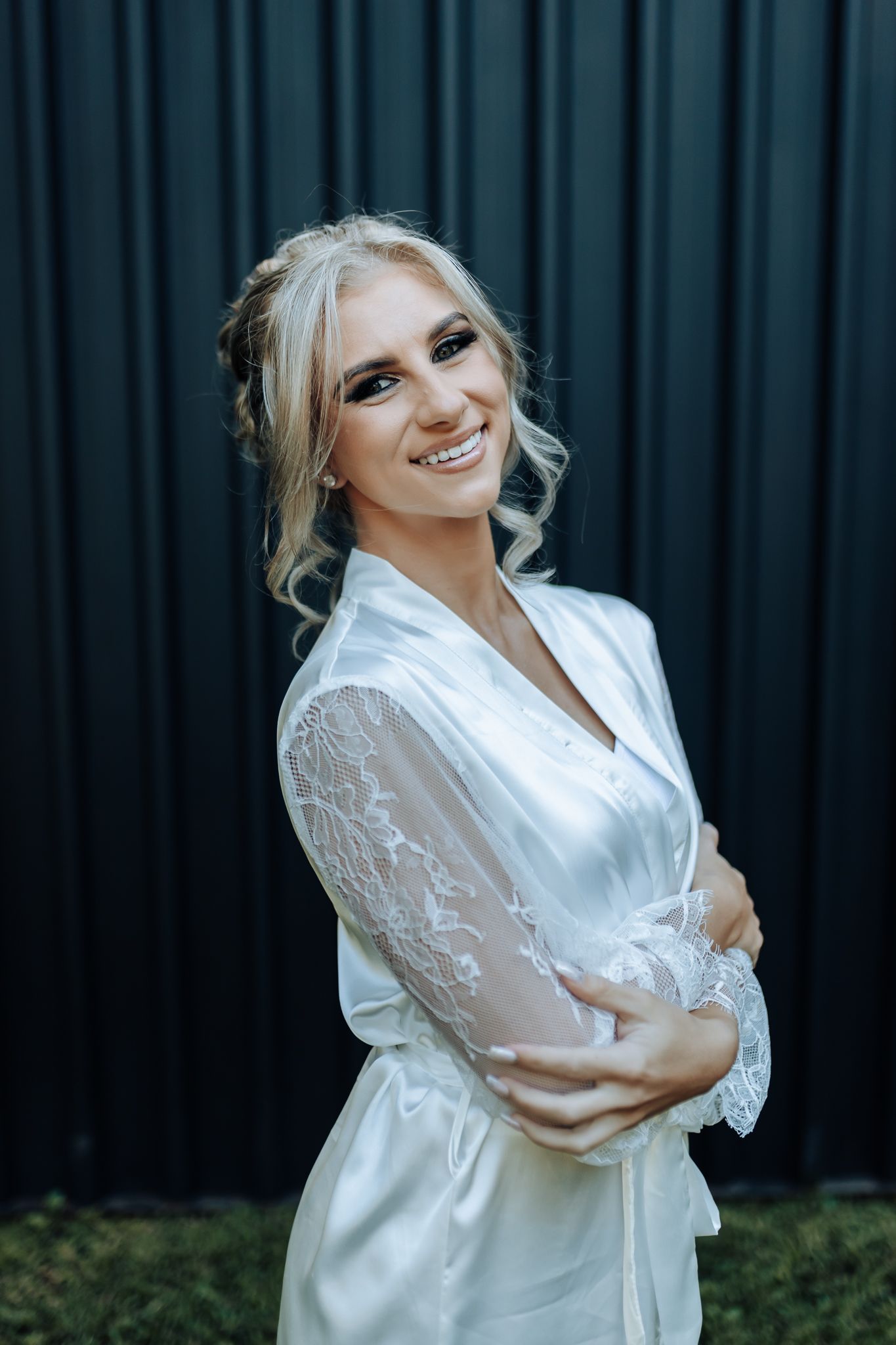 Pre-wedding portrait in white satin robe against dark background.