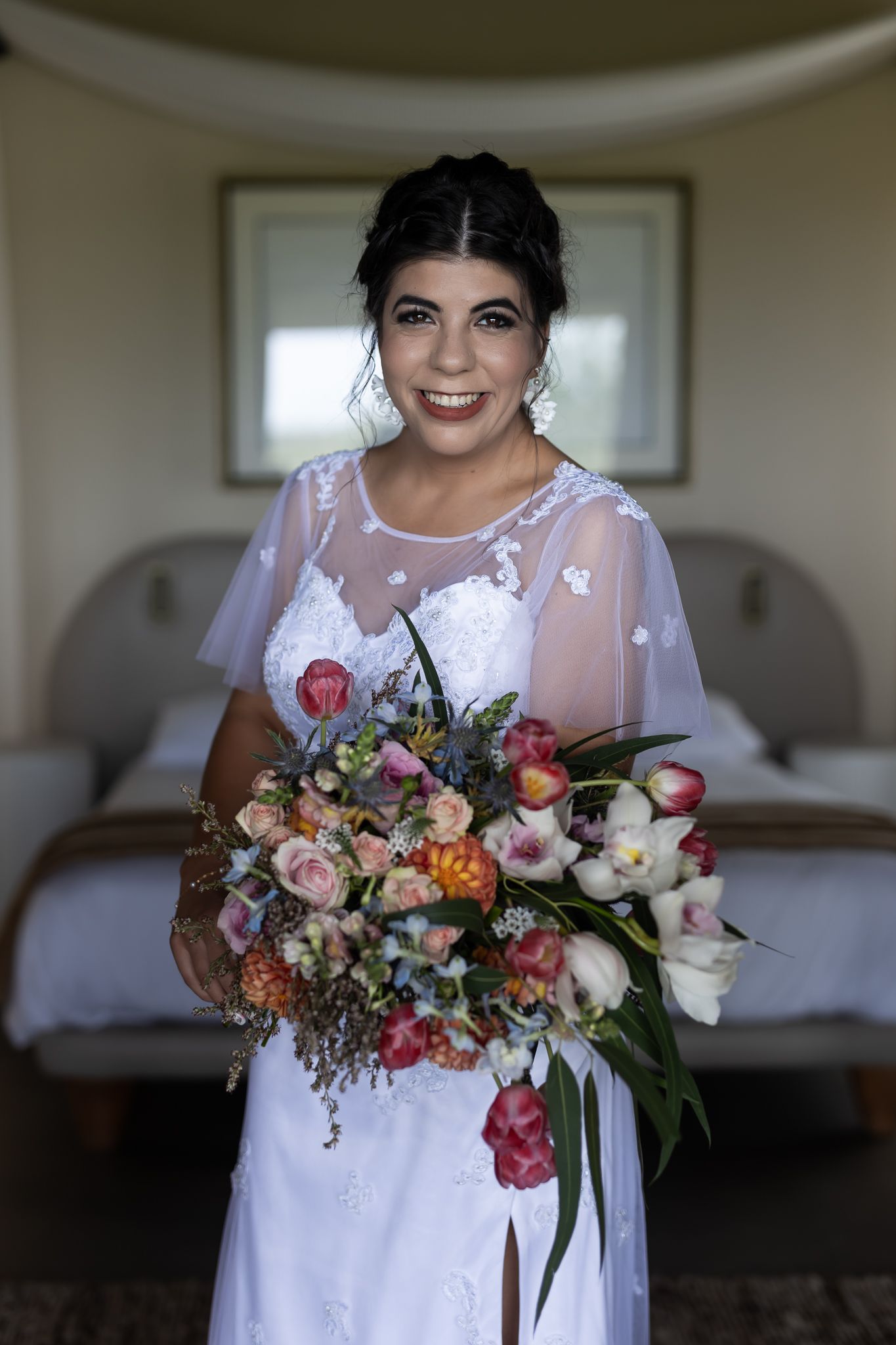 A person in a wedding dress holds a vibrant bouquet of mixed flowers.
