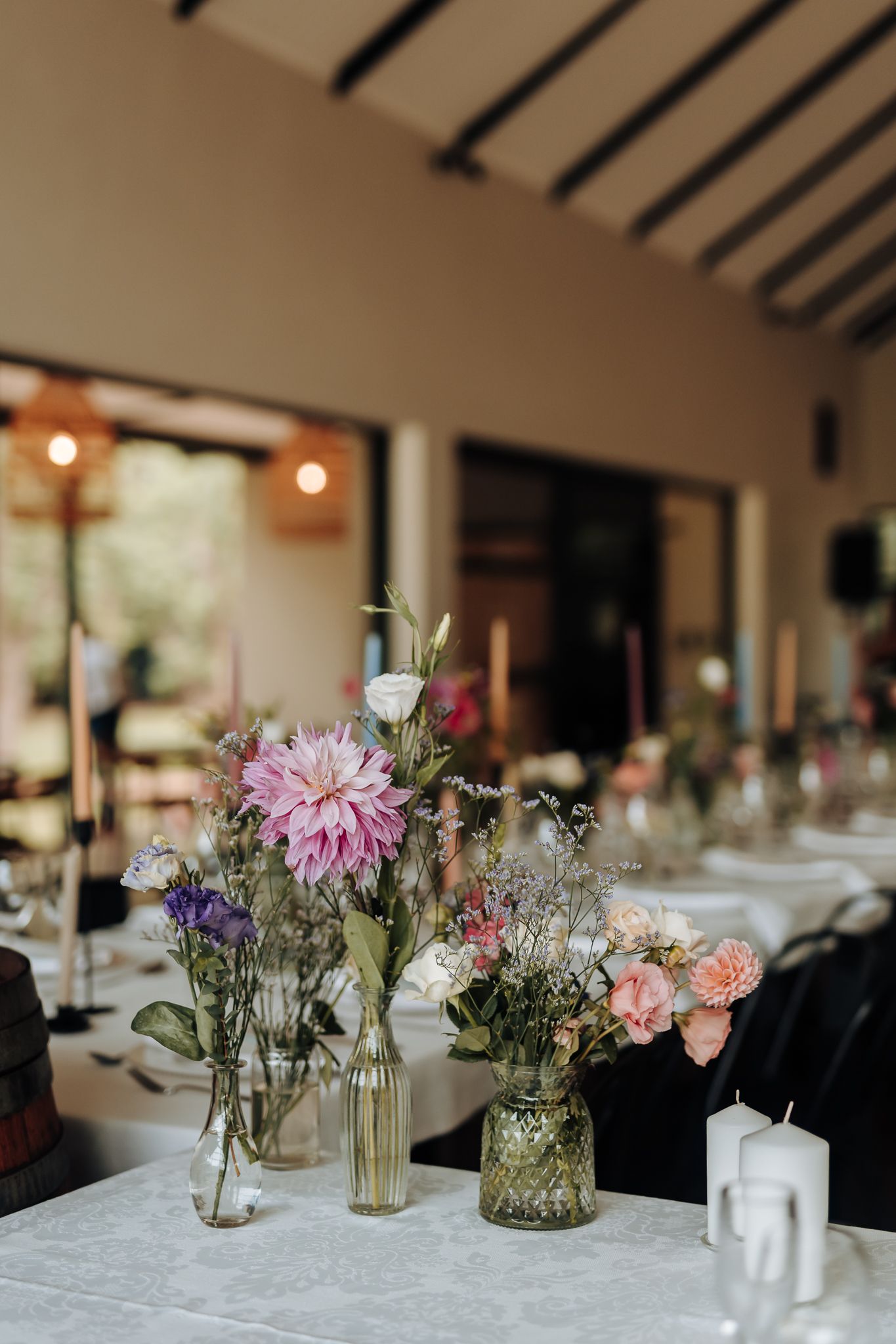 Romantic table setting with pink dahlias and mixed flowers in vintage glass vases.