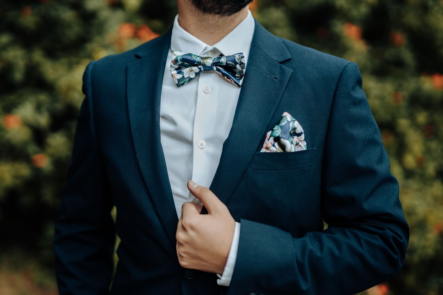 Close-up of navy suit jacket with patterned bow tie and matching pocket square.