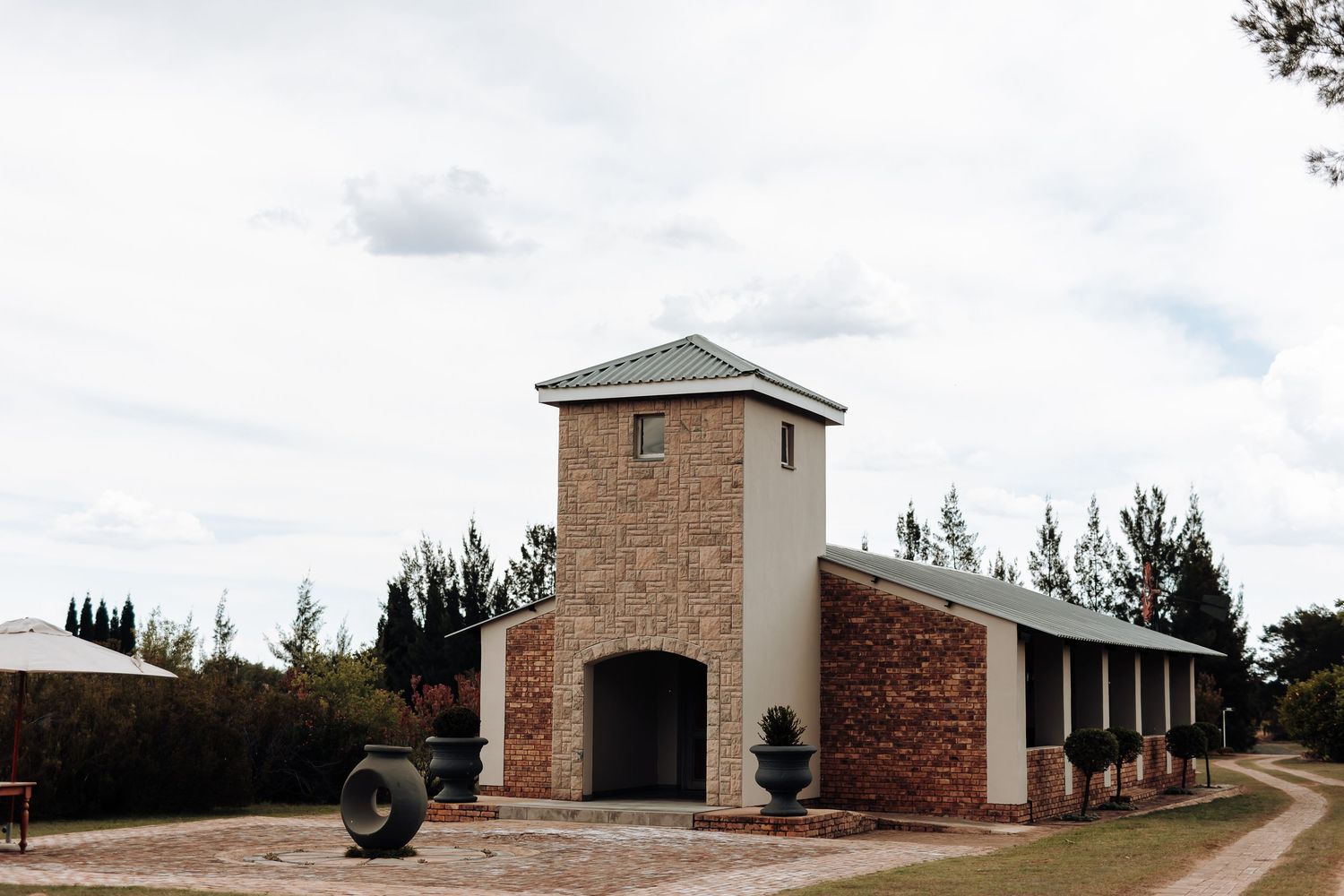 Stone and brick chapel building with tower entrance under cloudy sky.