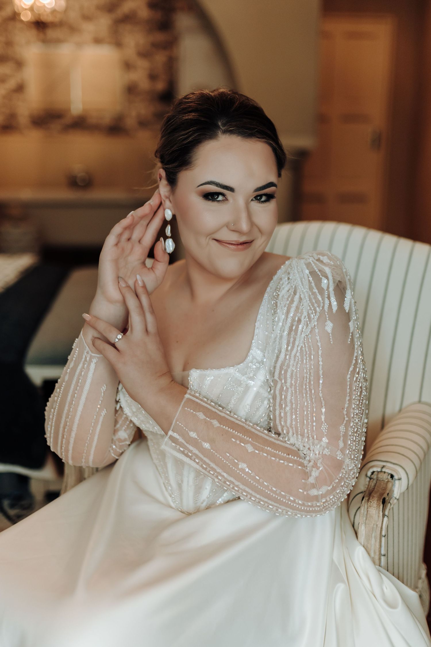 Intimate bridal photo highlighting detailed sleeves and statement drop earrings against stone walls.