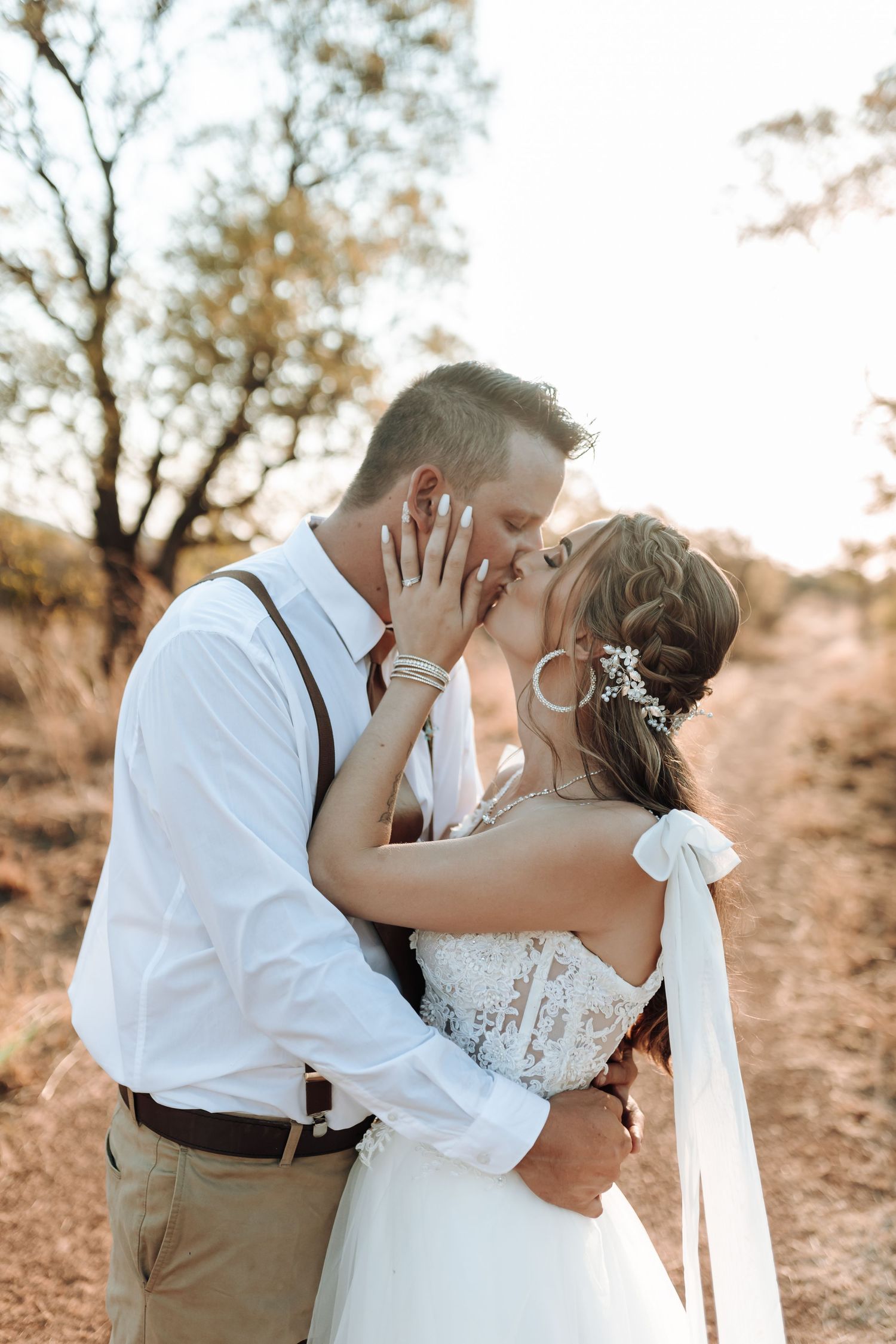 Intimate wedding moment captured in warm golden light on outdoor path.