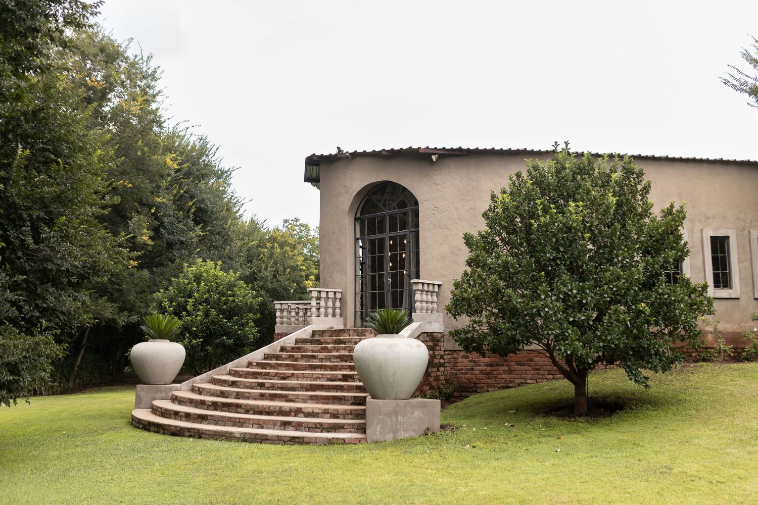 Mediterranean-style garden venue with curved stone staircase and large decorative planters.