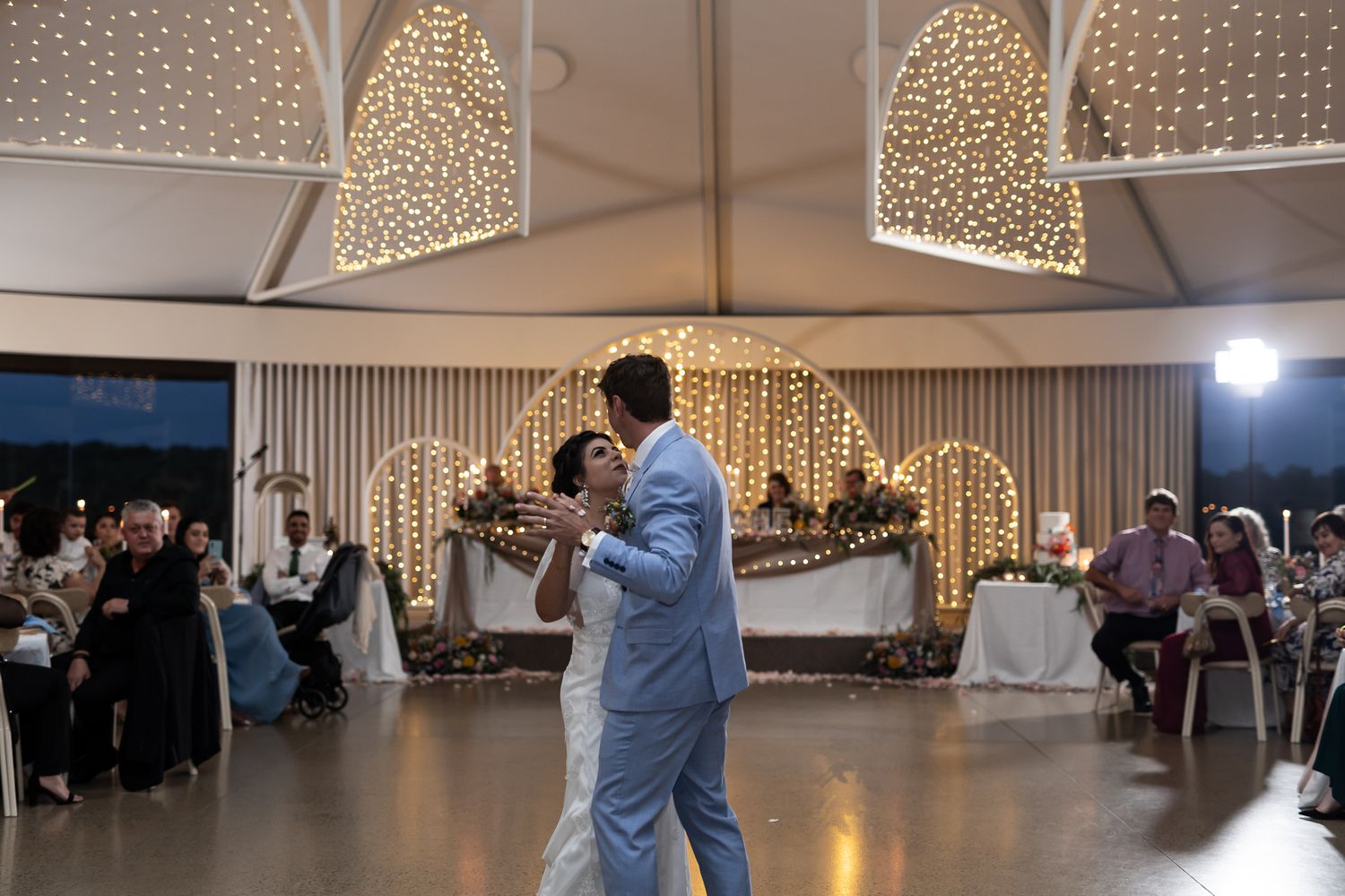 A romantic ballroom dance during a wedding celebration with twinkle light decorations in the background.