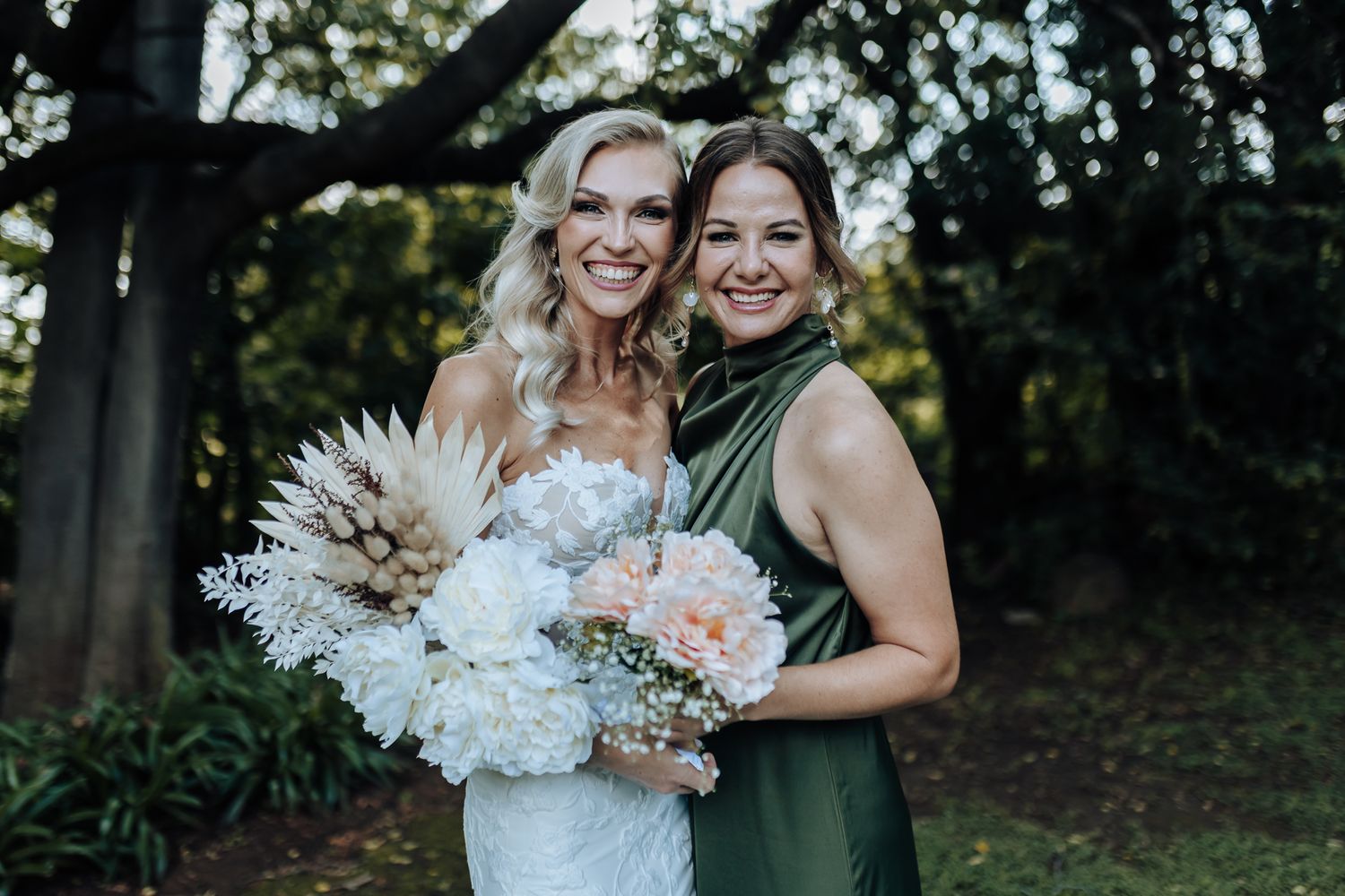 Joyful wedding photo with elegant bouquets featuring white and pink flowers against a natural backdrop.