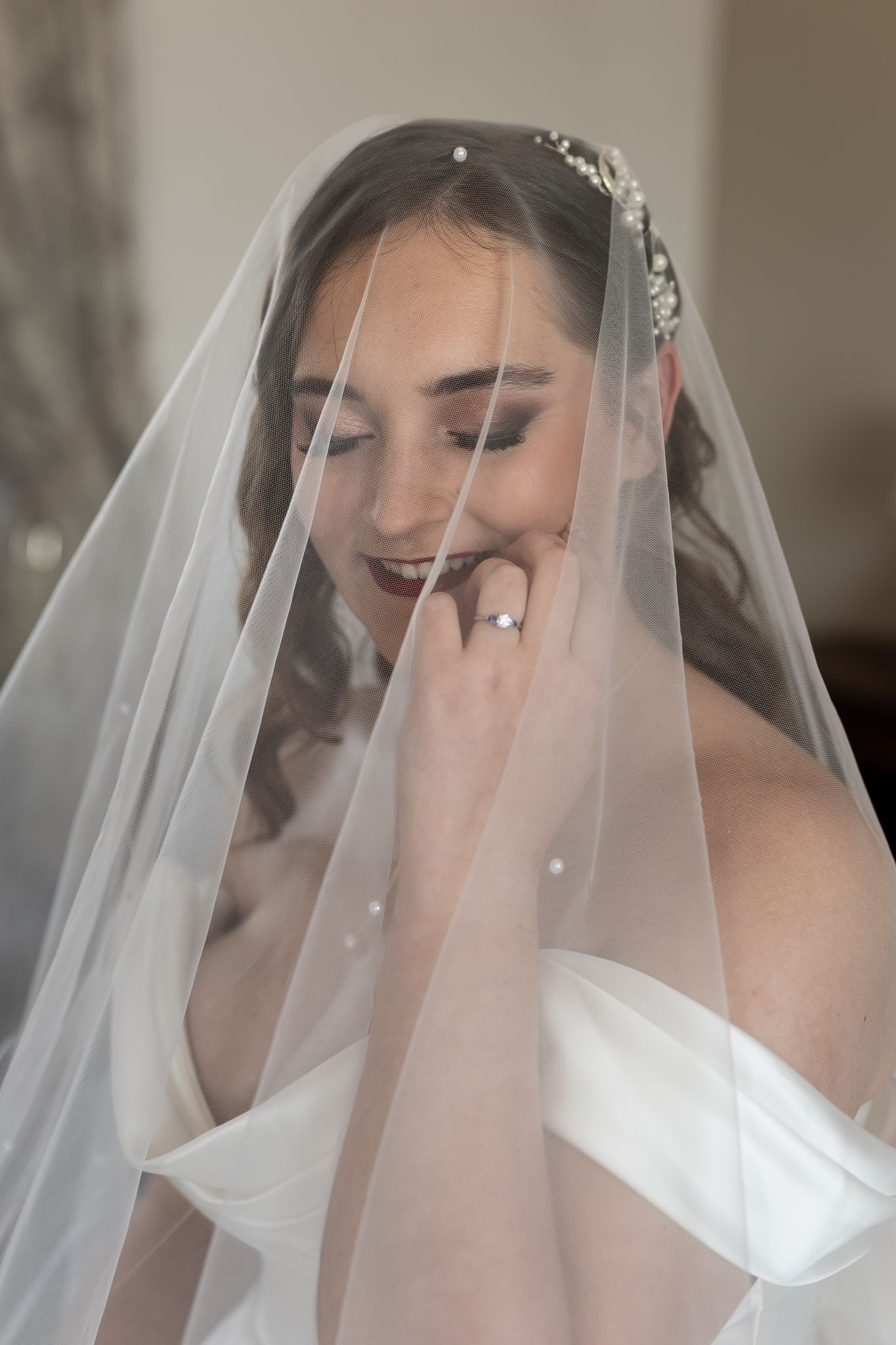 Intimate moment captured through sheer wedding veil showing elegant bridal details.