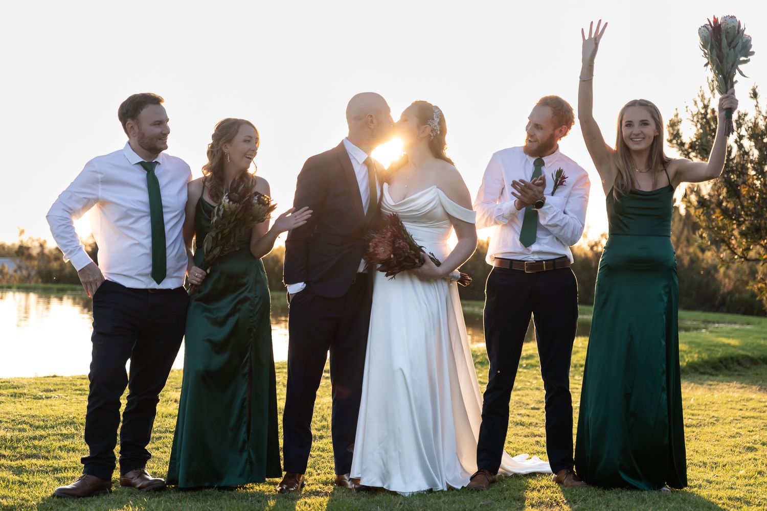 Sunlit wedding celebration with party members dancing and laughing outdoors.