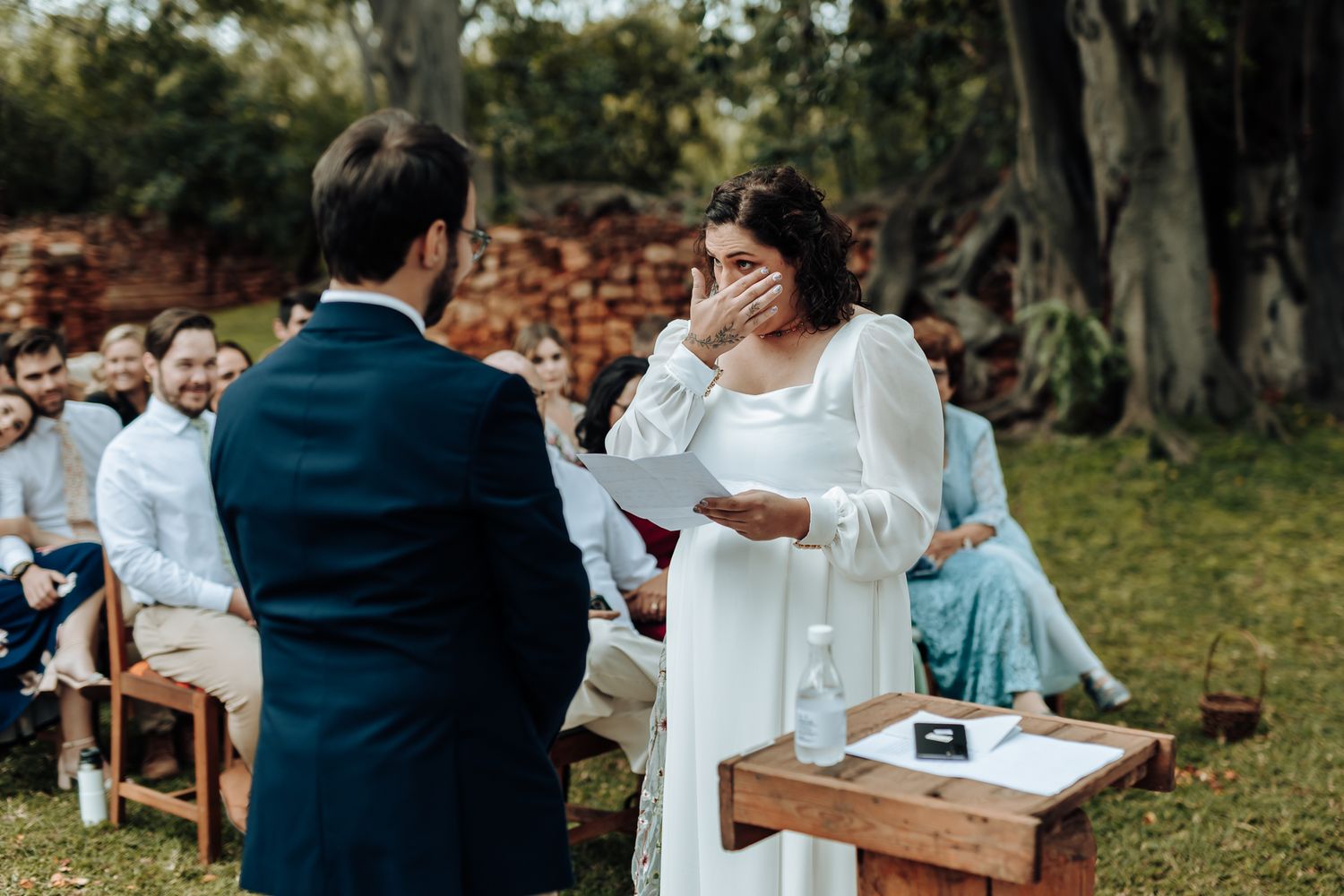 An emotional moment unfolds during a garden wedding ceremony as vows are exchanged.