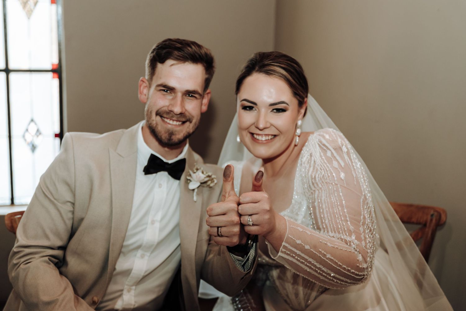 Wedding couple gives enthusiastic thumbs up while celebrating their special day.