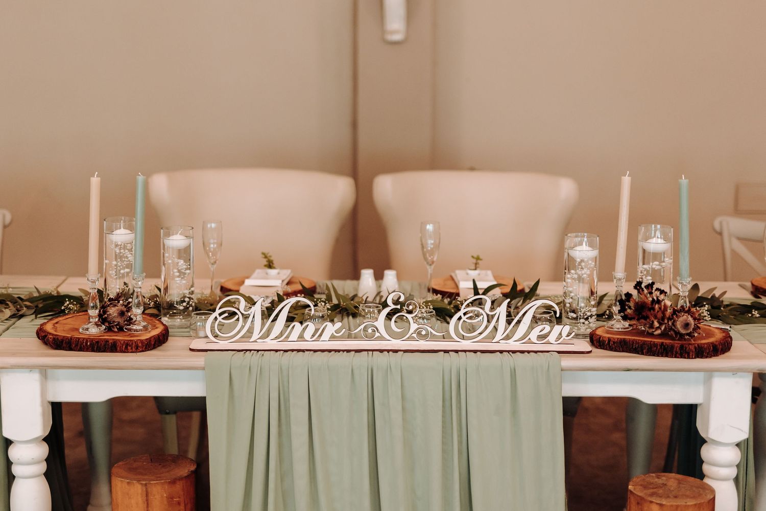 Wedding head table decorated with 'Mr & Mrs' sign and rustic autumn centerpieces.