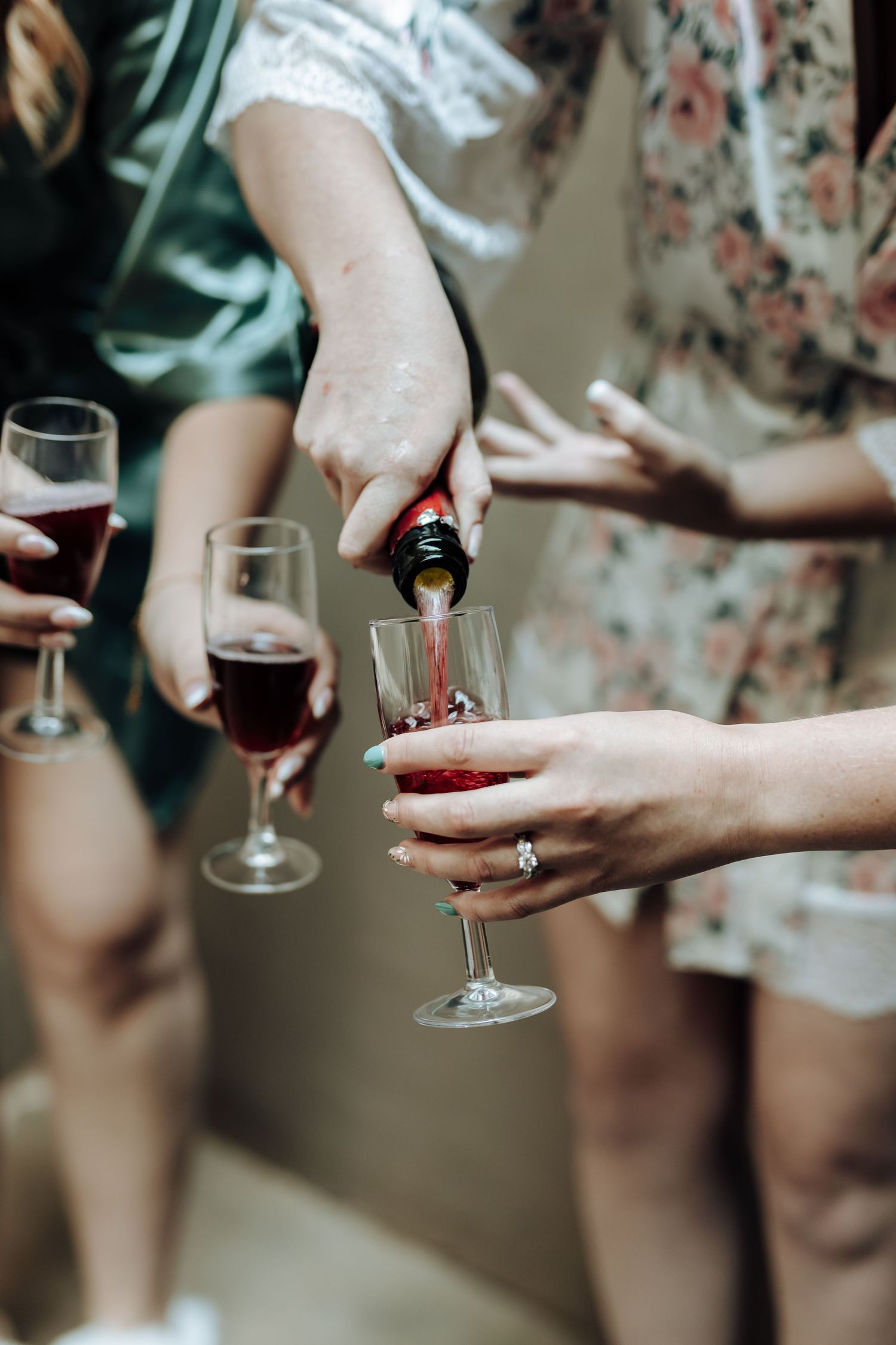 Close up of hands pouring red wine into glasses during celebration.