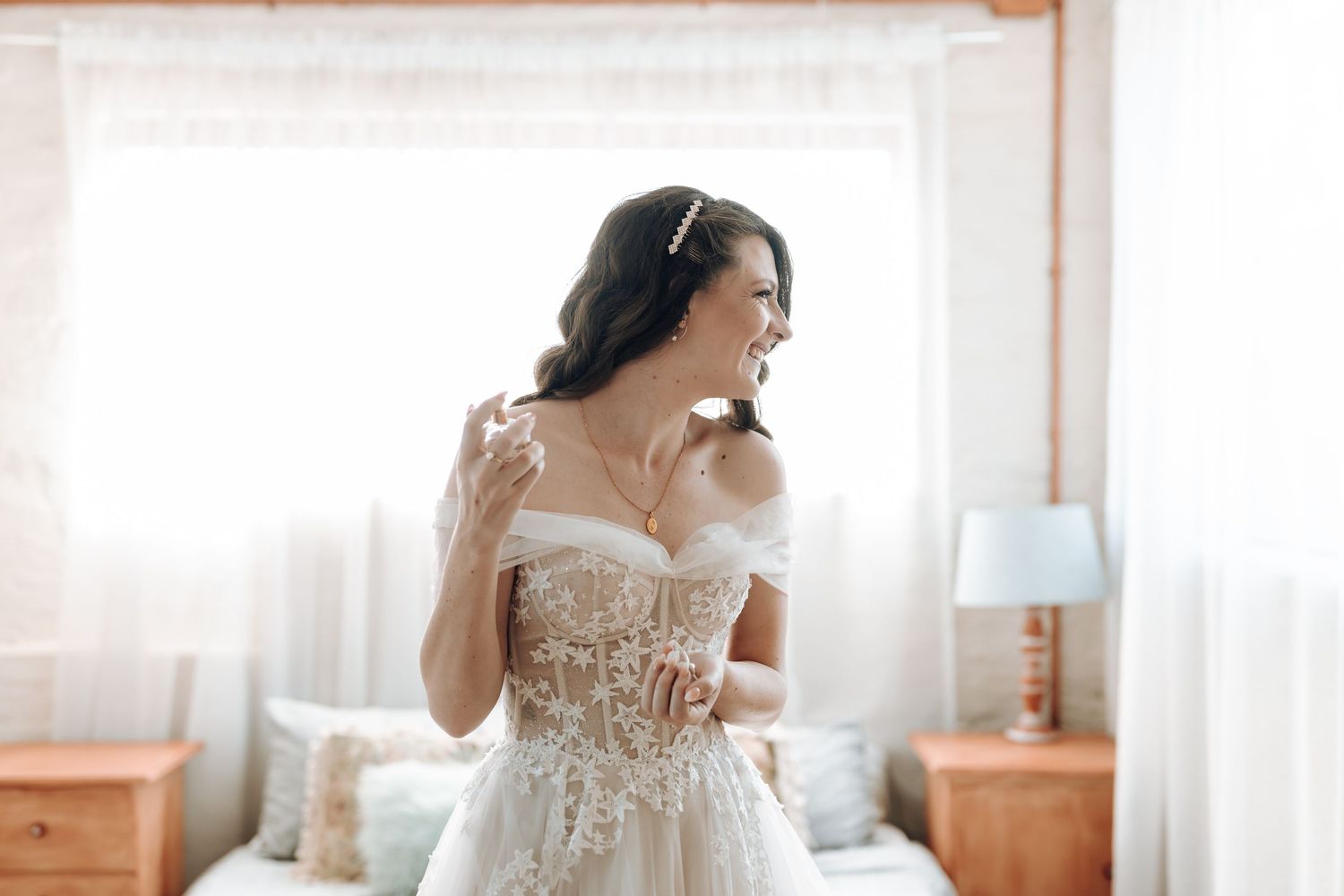 Sunlit bridal portrait showcasing intricate lace details of an off-shoulder wedding gown.