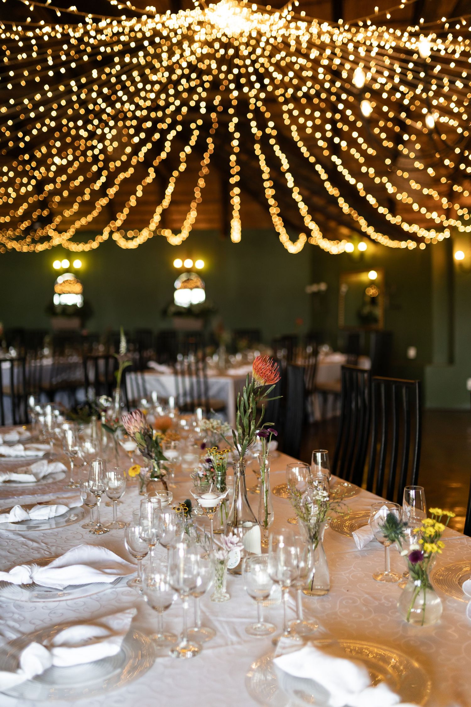 Elegant table setting under cascading fairy lights at wedding reception.