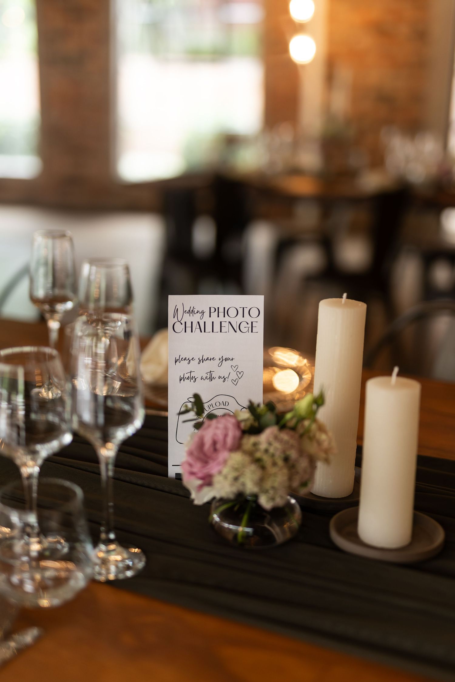 An elegant table setting with wine glasses, candles and a photo challenge card for wedding guests.