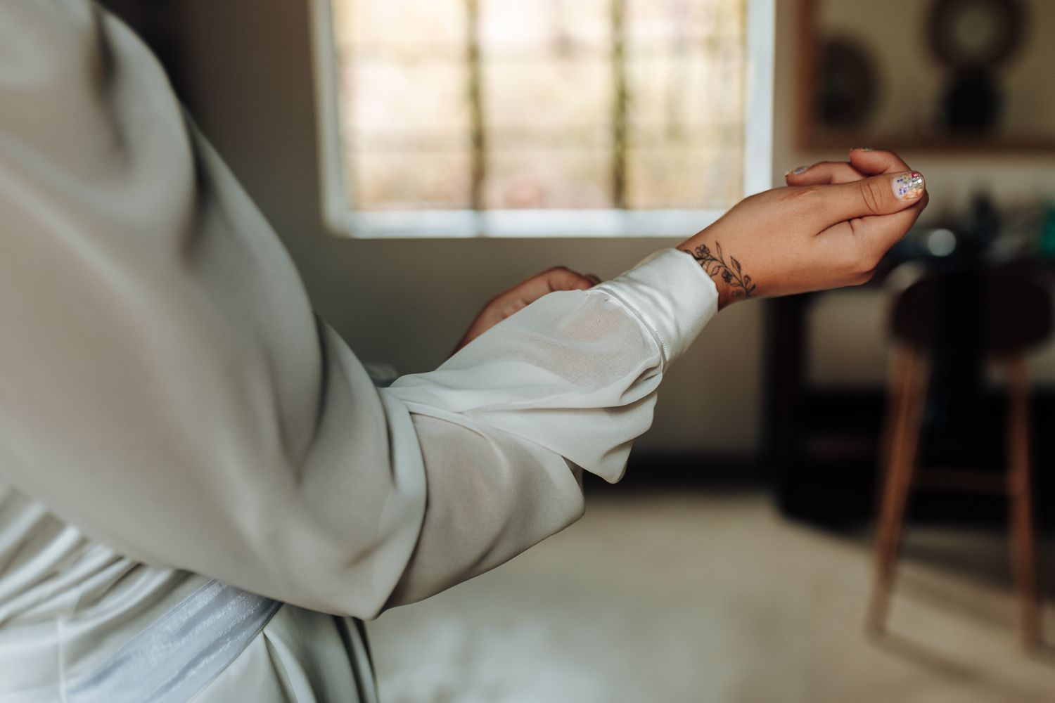 Close-up detail shot of a cream-colored dress sleeve and arm in soft natural lighting.