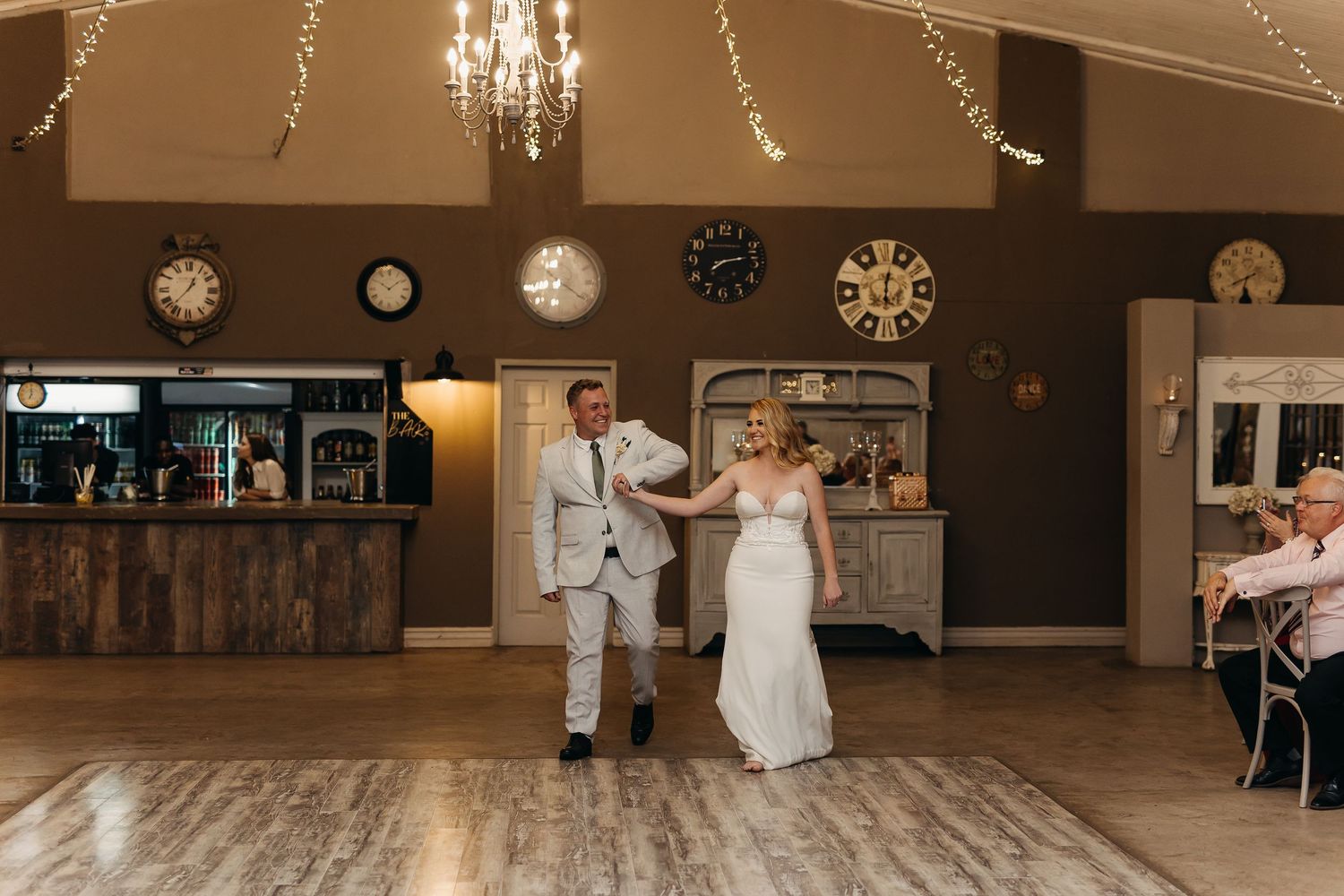 A wedding celebration in a rustic venue decorated with string lights and vintage clocks.