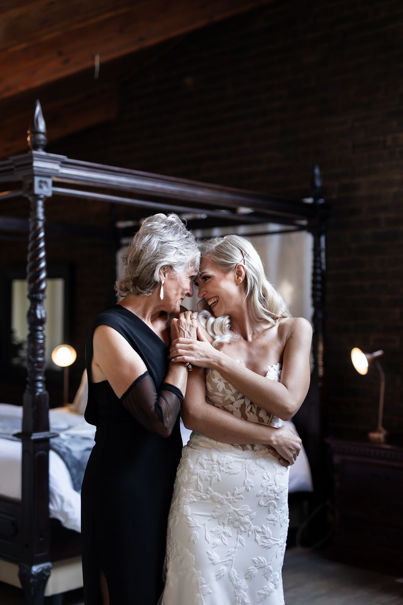 A tender moment captured between two people in a room with a four-poster bed.