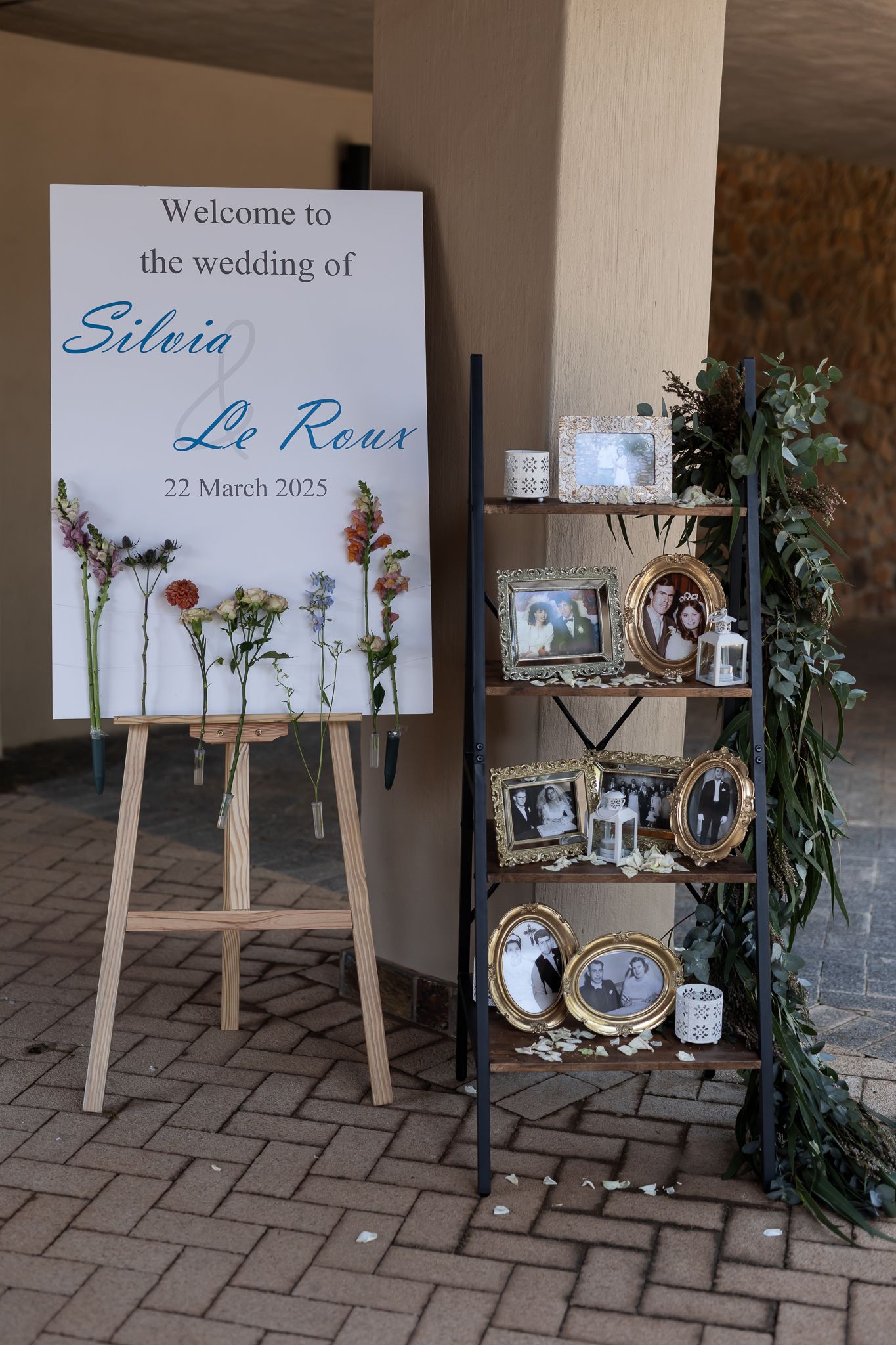 Rustic wedding welcome sign display with wooden ladder shelf and decorative memorabilia.