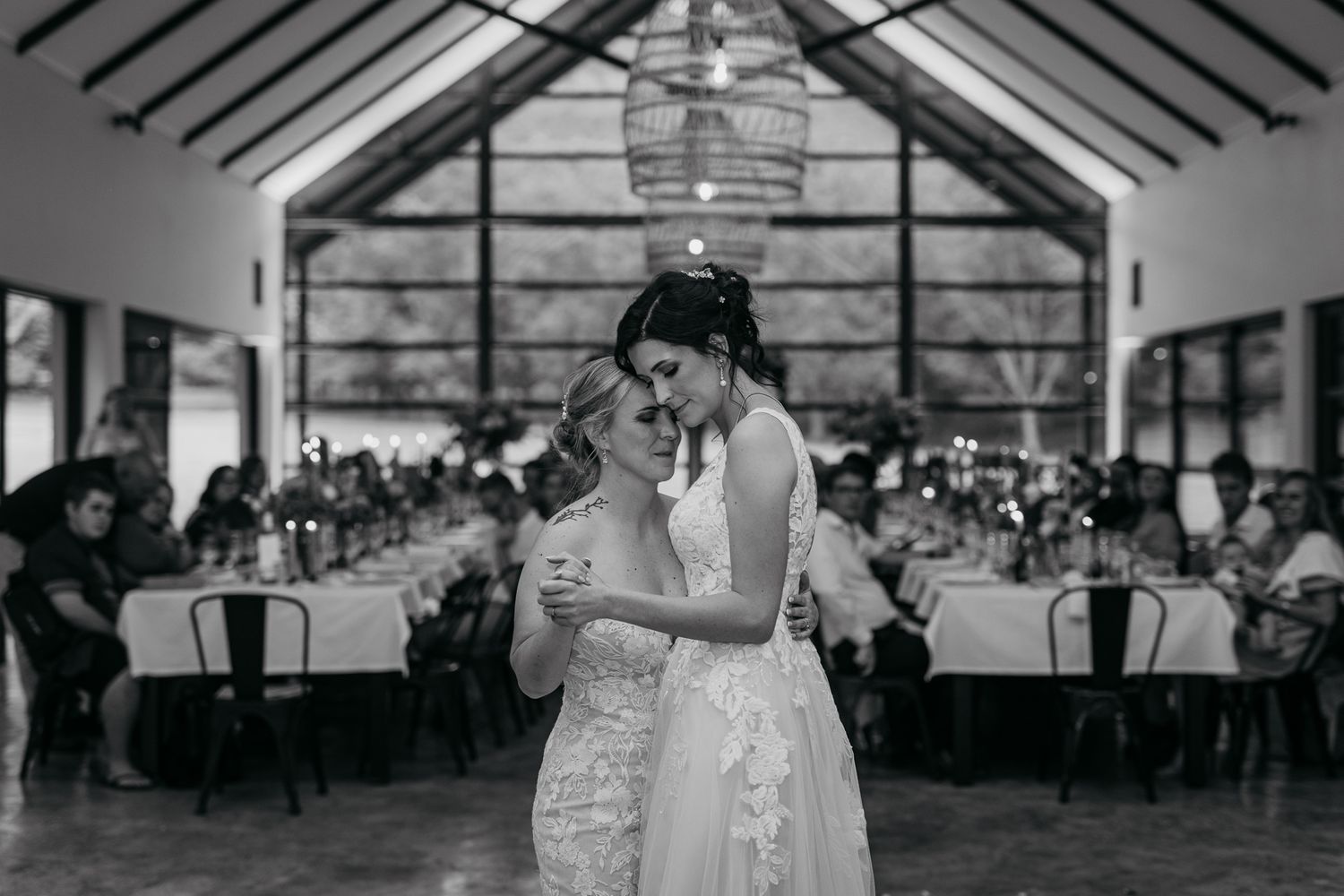 A romantic first dance in an elegant reception hall with vaulted ceilings and large windows.