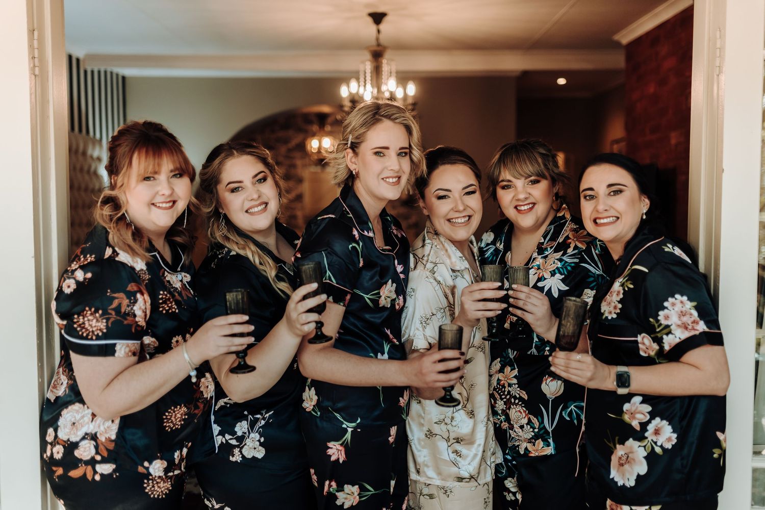 Wedding party group pose in coordinated black floral robes with bride in white silk.