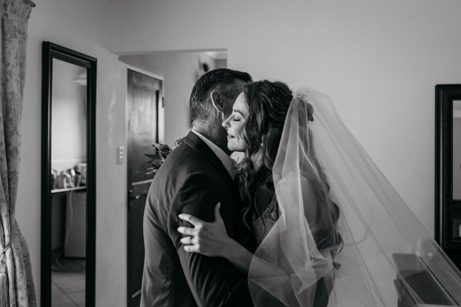 Black and white intimate moment between bride and groom during wedding preparations.