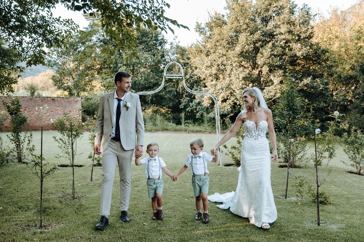 Family holds hands while walking together during outdoor wedding photos.