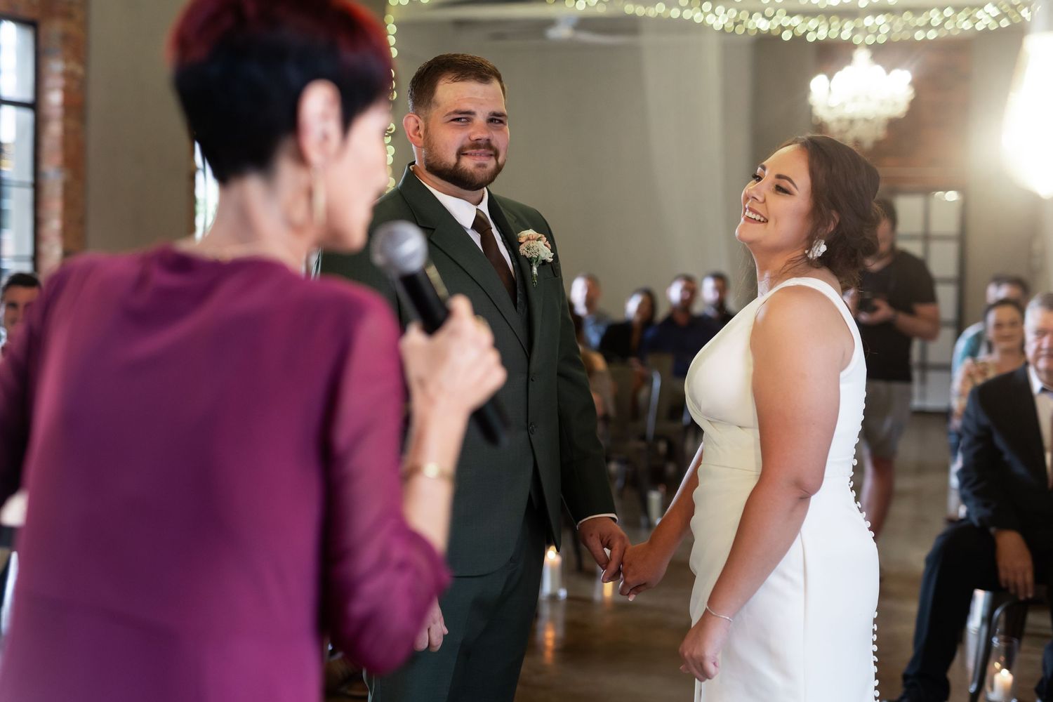 An intimate wedding ceremony moment captured in a beautifully lit venue with string lights.