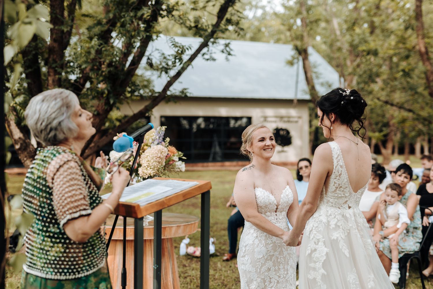 Wedding ceremony in progress at rustic outdoor venue with wooden podium.