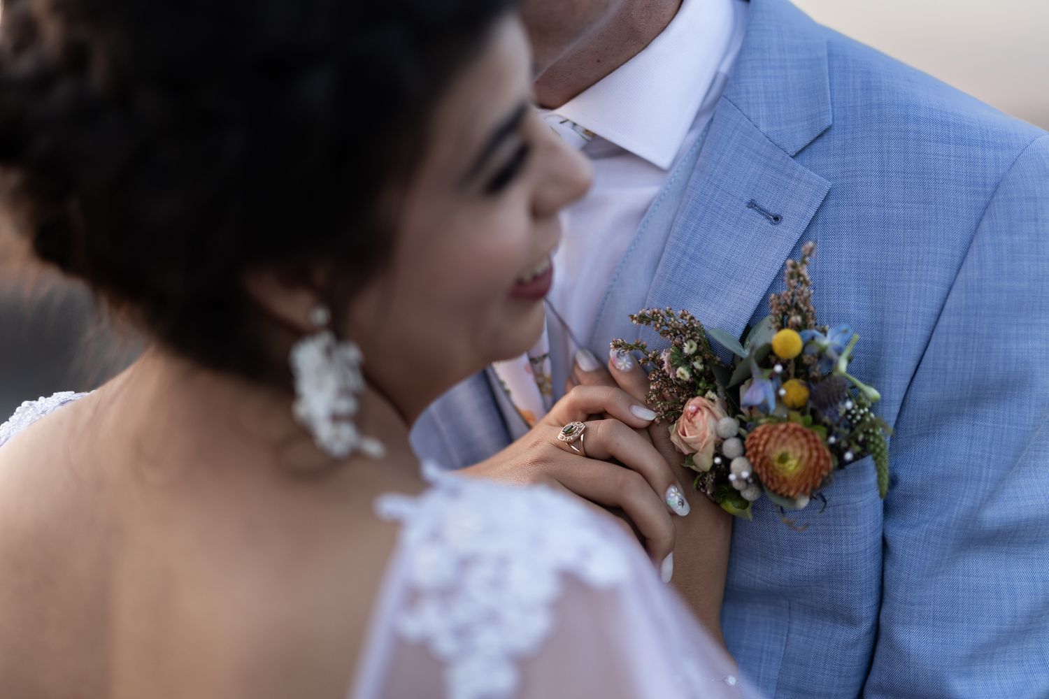 Wedding couple sharing intimate moment with focus on groom's boutonniere.