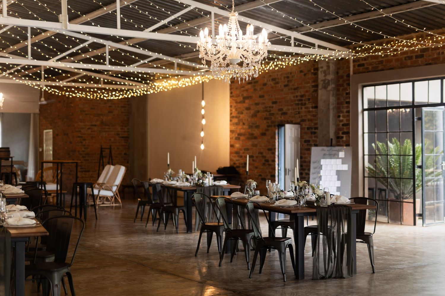 An industrial-chic wedding venue with exposed brick walls and string lights creating a warm ambiance.