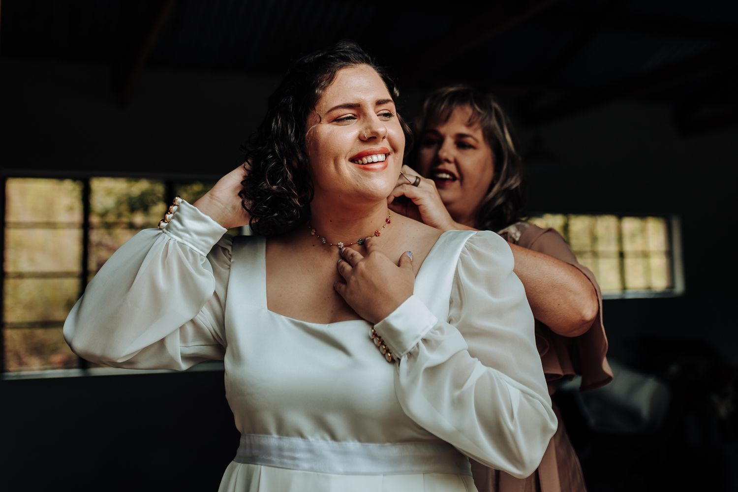 Joyful candid moment between two people laughing together in formal attire.