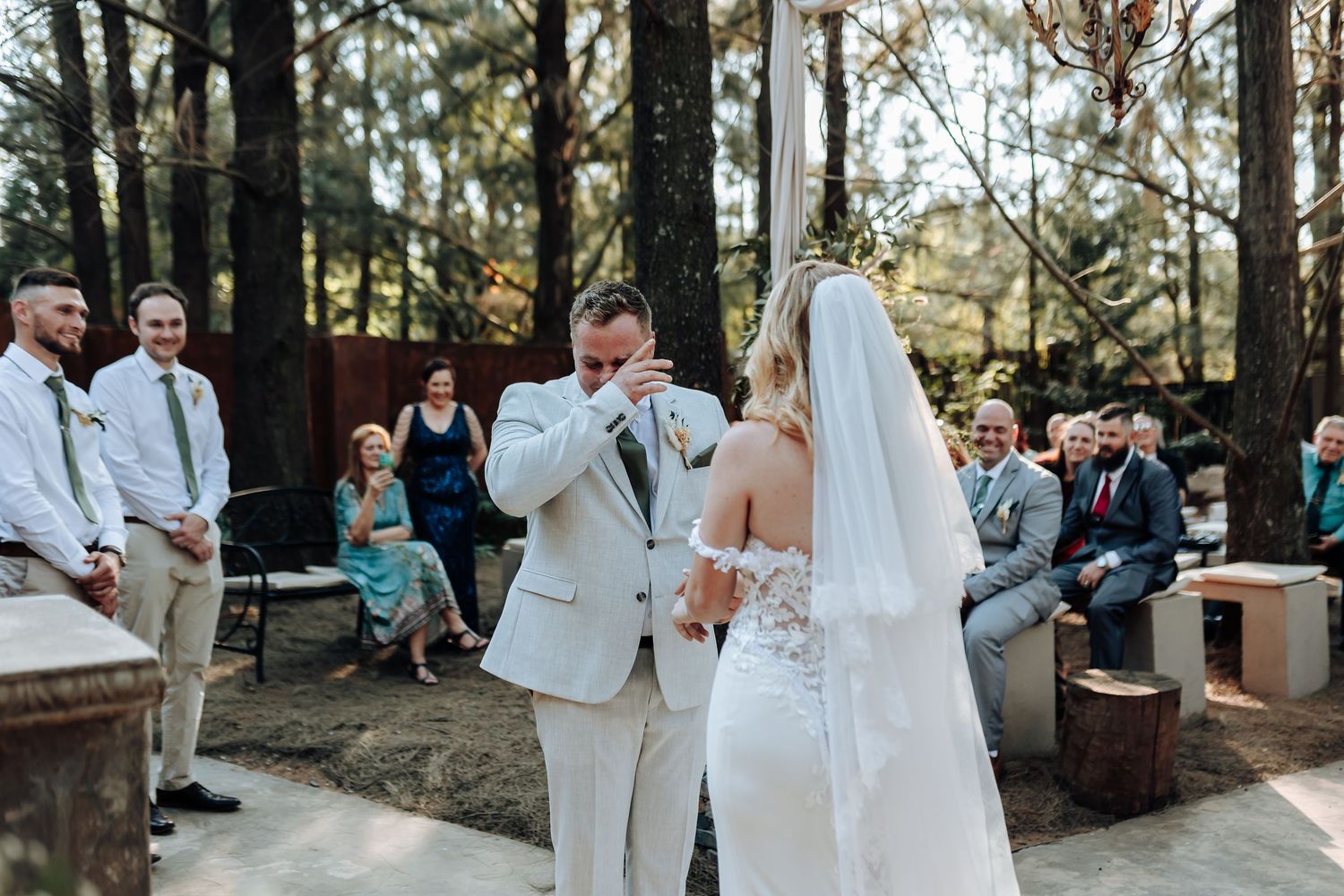 Emotional wedding ceremony moment in a rustic outdoor forest setting.