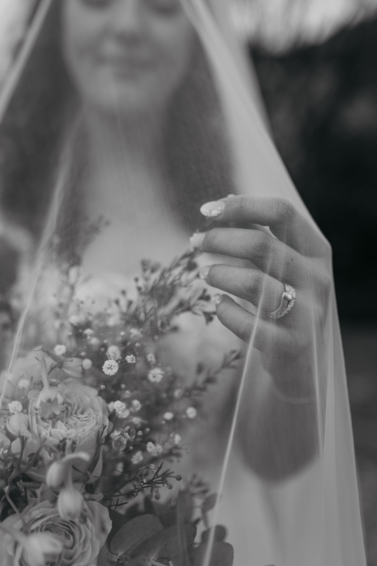 A dreamy black and white photo montage of a bride holding an elegant floral bouquet with delicate white flowers and greenery.