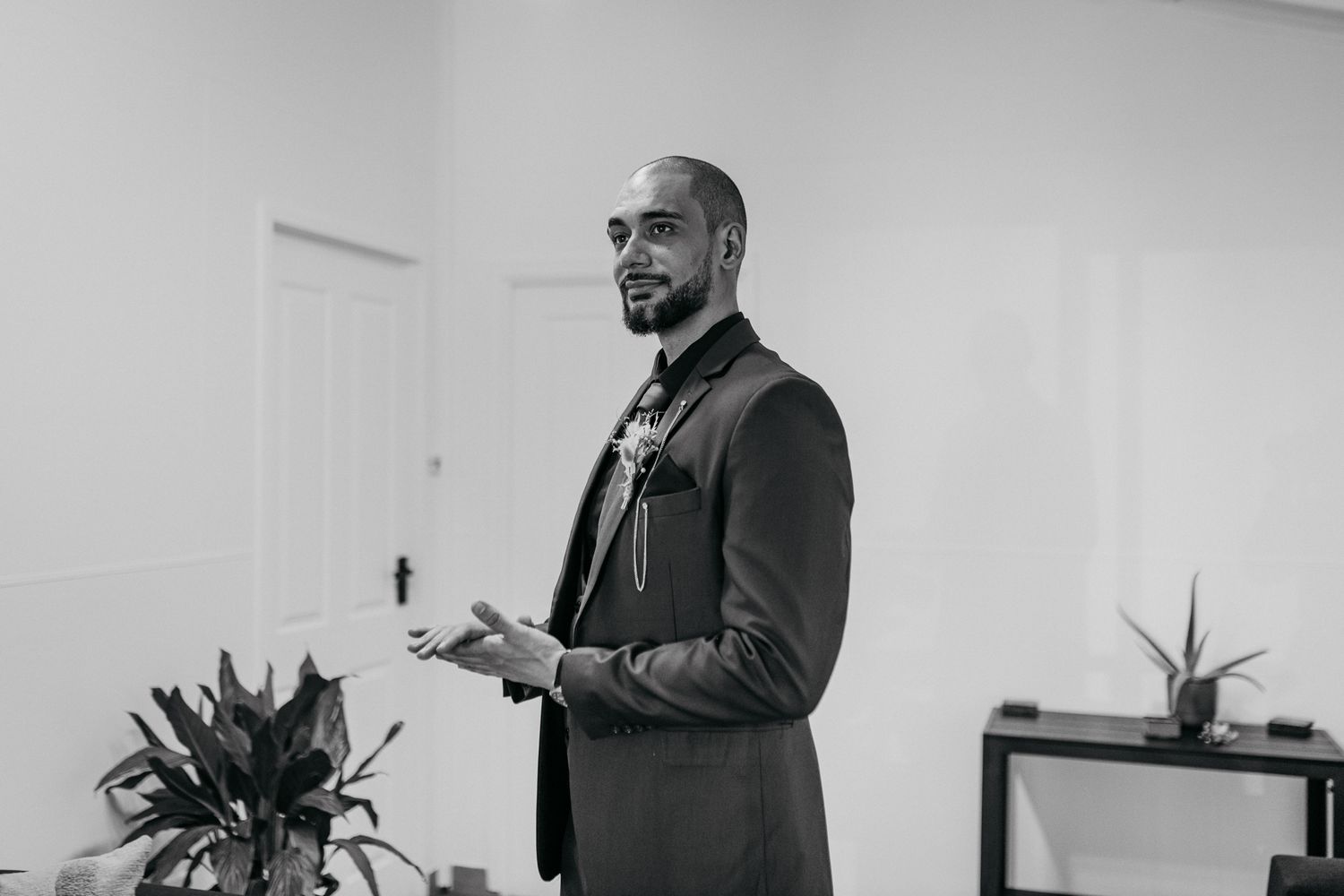 Person speaking while standing in business attire against white wall.