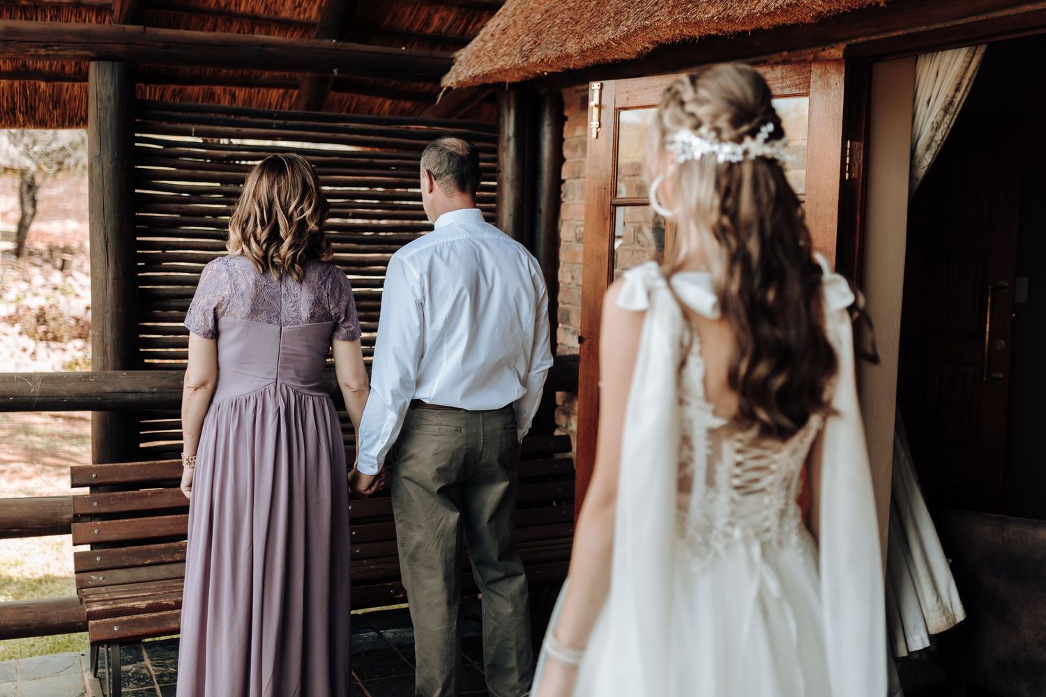 Wedding party in muted tones gathers in a rustic wooden venue.