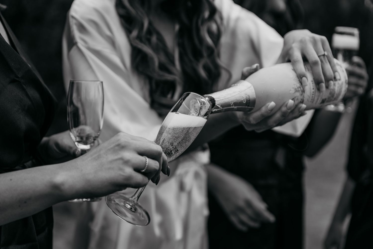 Black and white photo of champagne being poured into glasses during celebration.