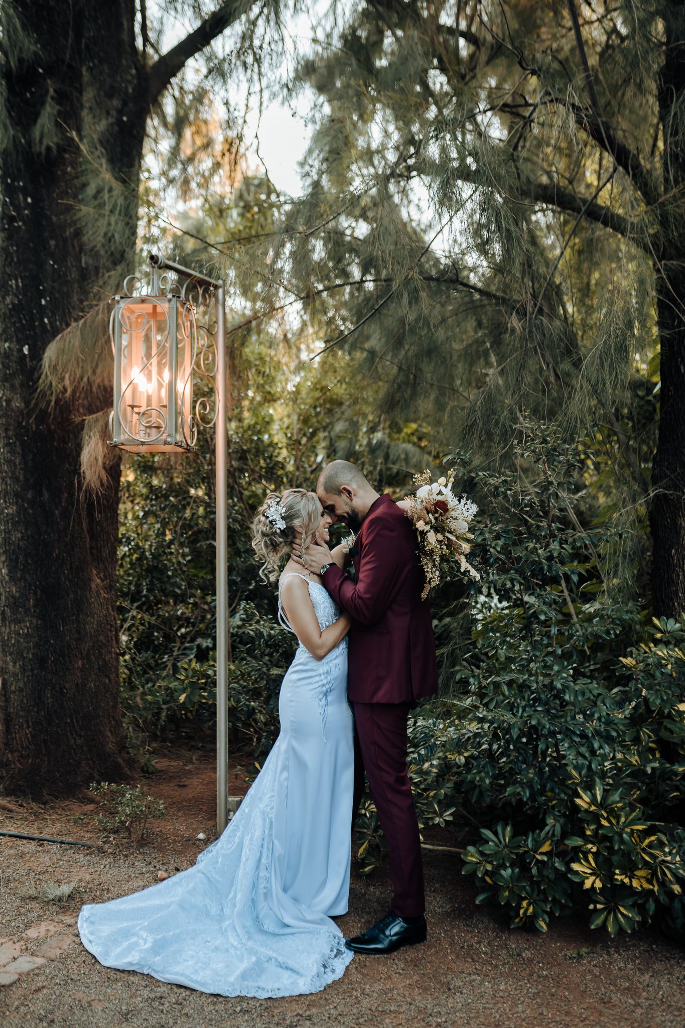 Wedding couple shares tender moment beneath illuminated vintage lantern.