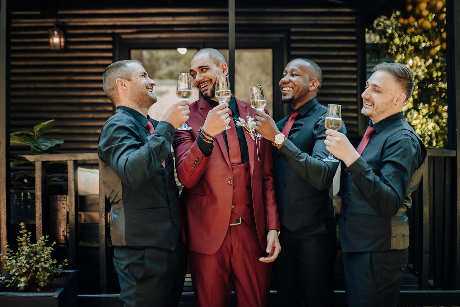 Formal group enjoying drinks and laughter at an outdoor celebration.