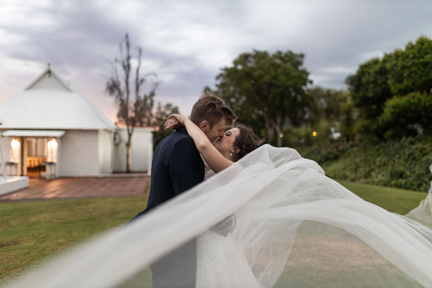 Wedding couple sharing intimate moment as veil flows dramatically in foreground.