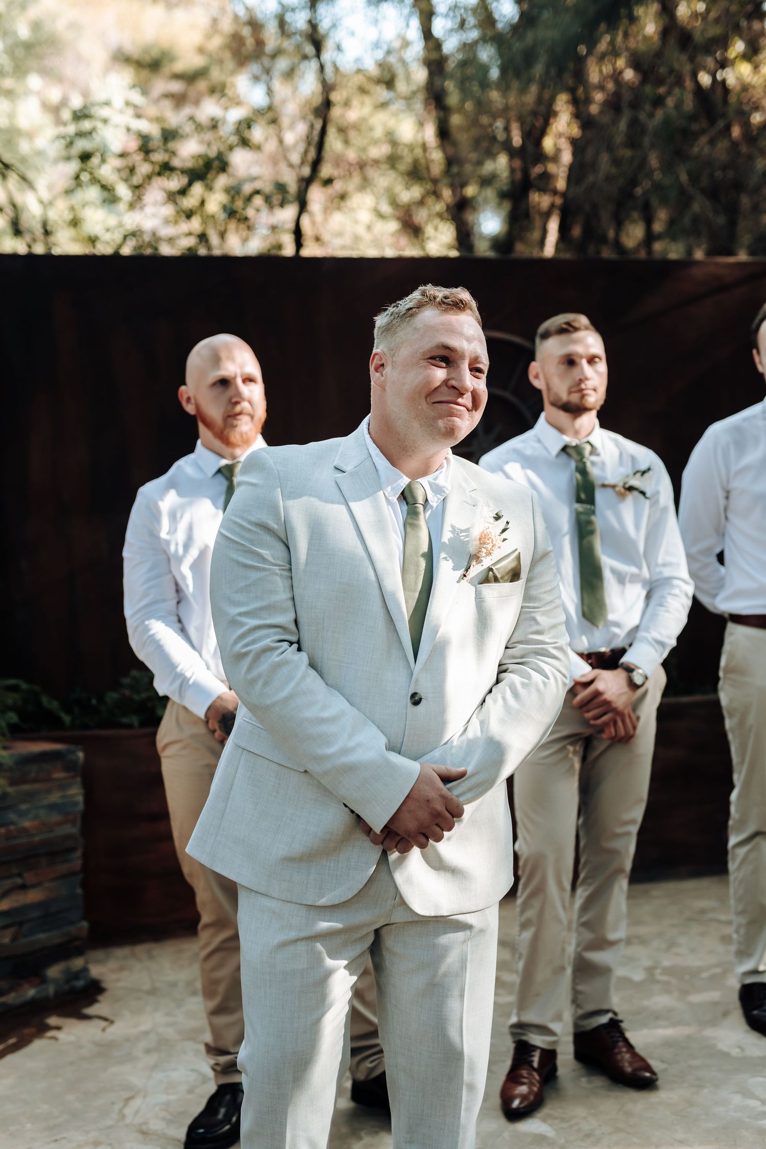 A groom and groomsmen stand at attention during a forest wedding ceremony.